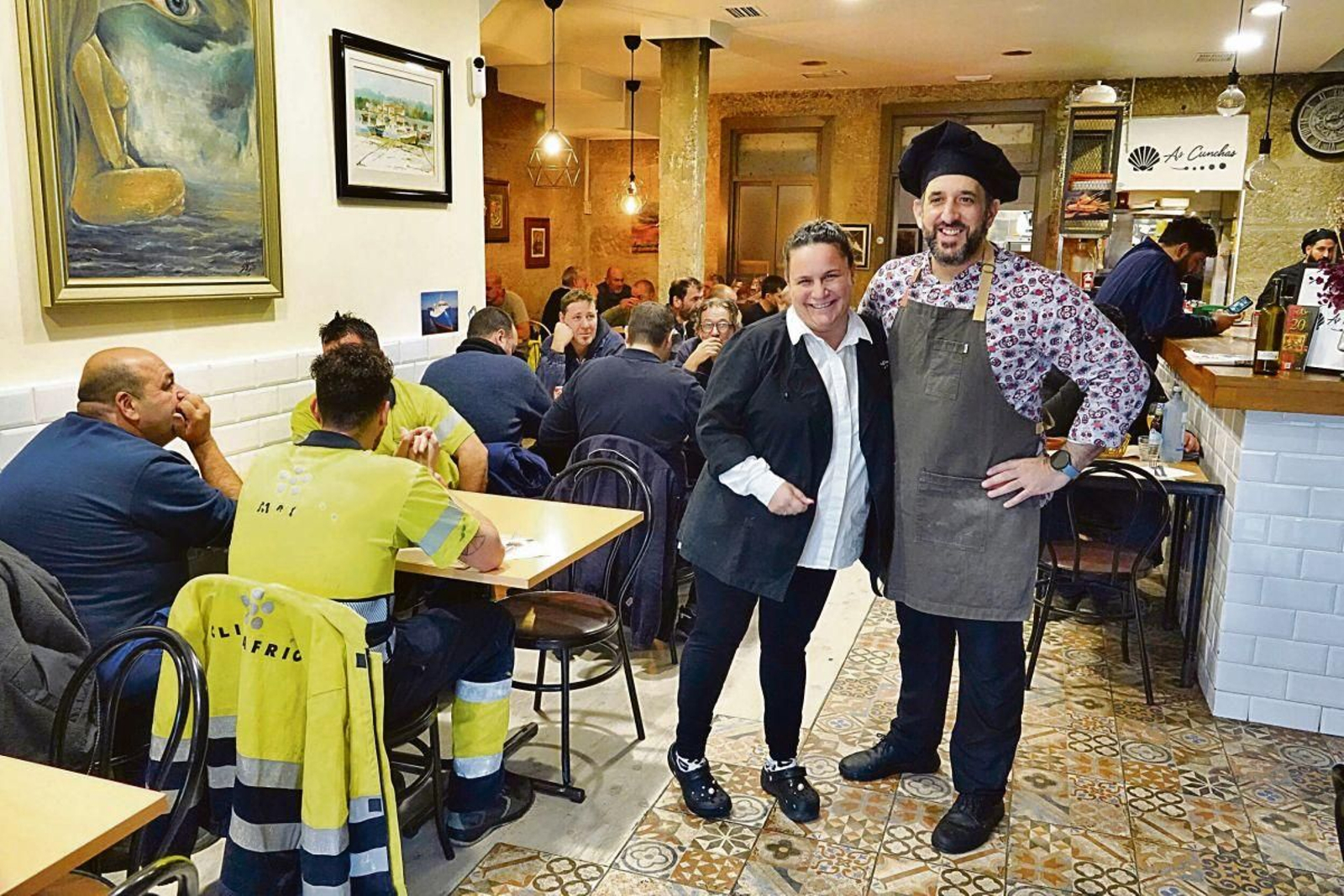 María, propietaria de As Cunchas, junto con personal de su local y comensales.