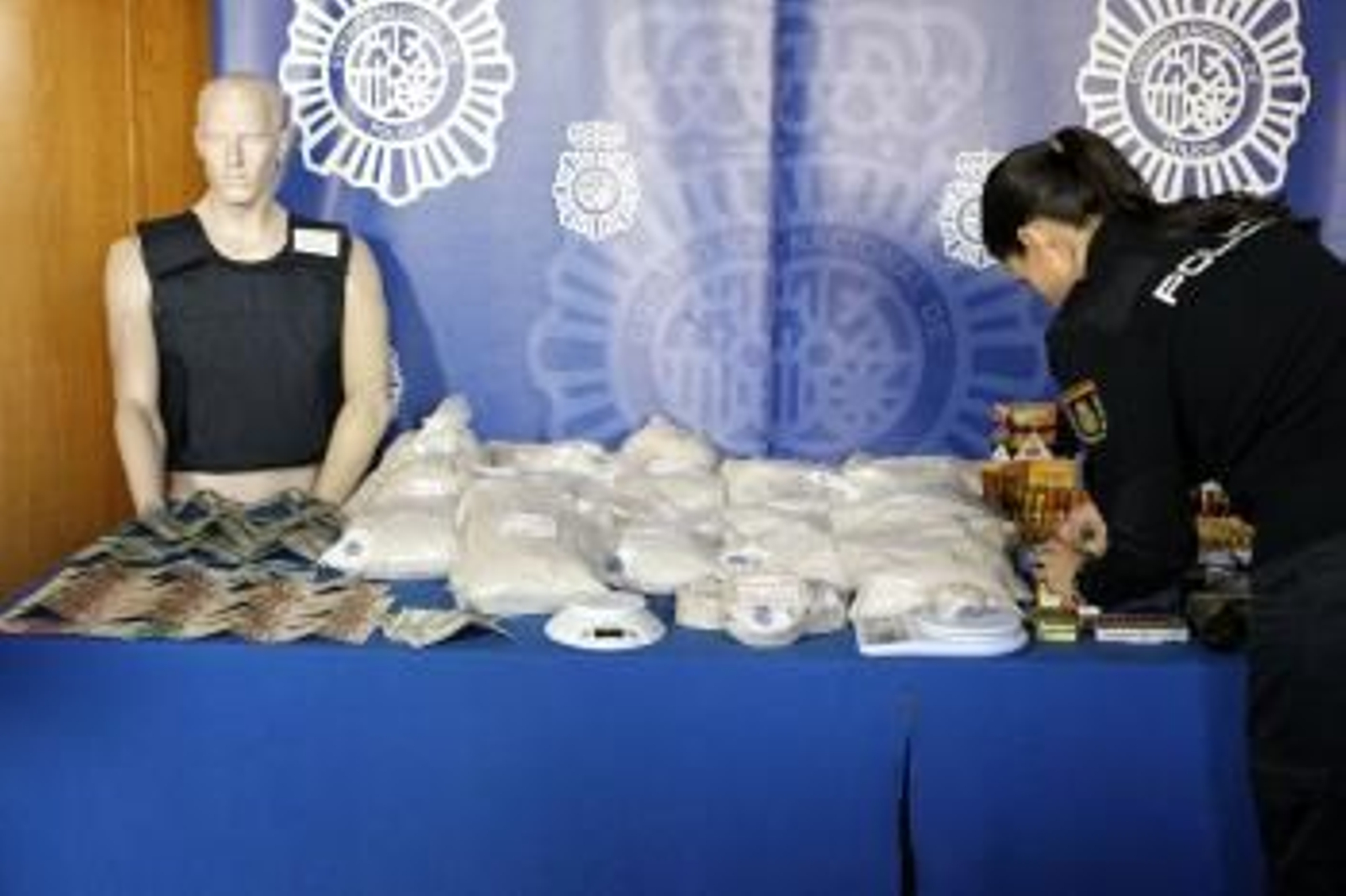 Una agente de la Policía Nacional coloca Los 45 kilos de heroína y resto de material intervenido por las Fuerzas de Seguridad tras la detención del denominado 'Señor de la droga'.