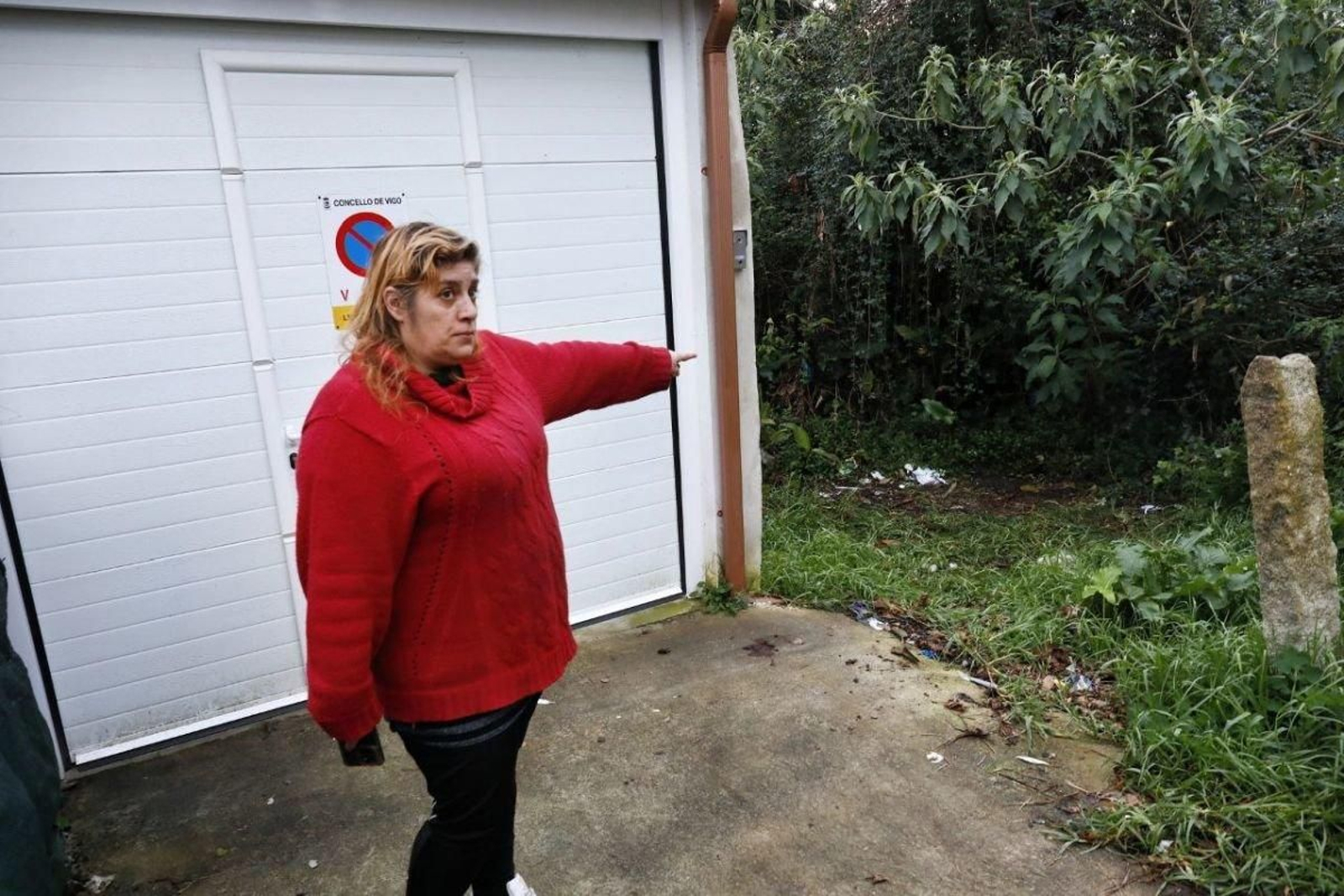 Una vecina de la rúa Espedrigada señala el lugar junto a la maleza en la que apareció la maleta con el cadáver desmembrado dentro.