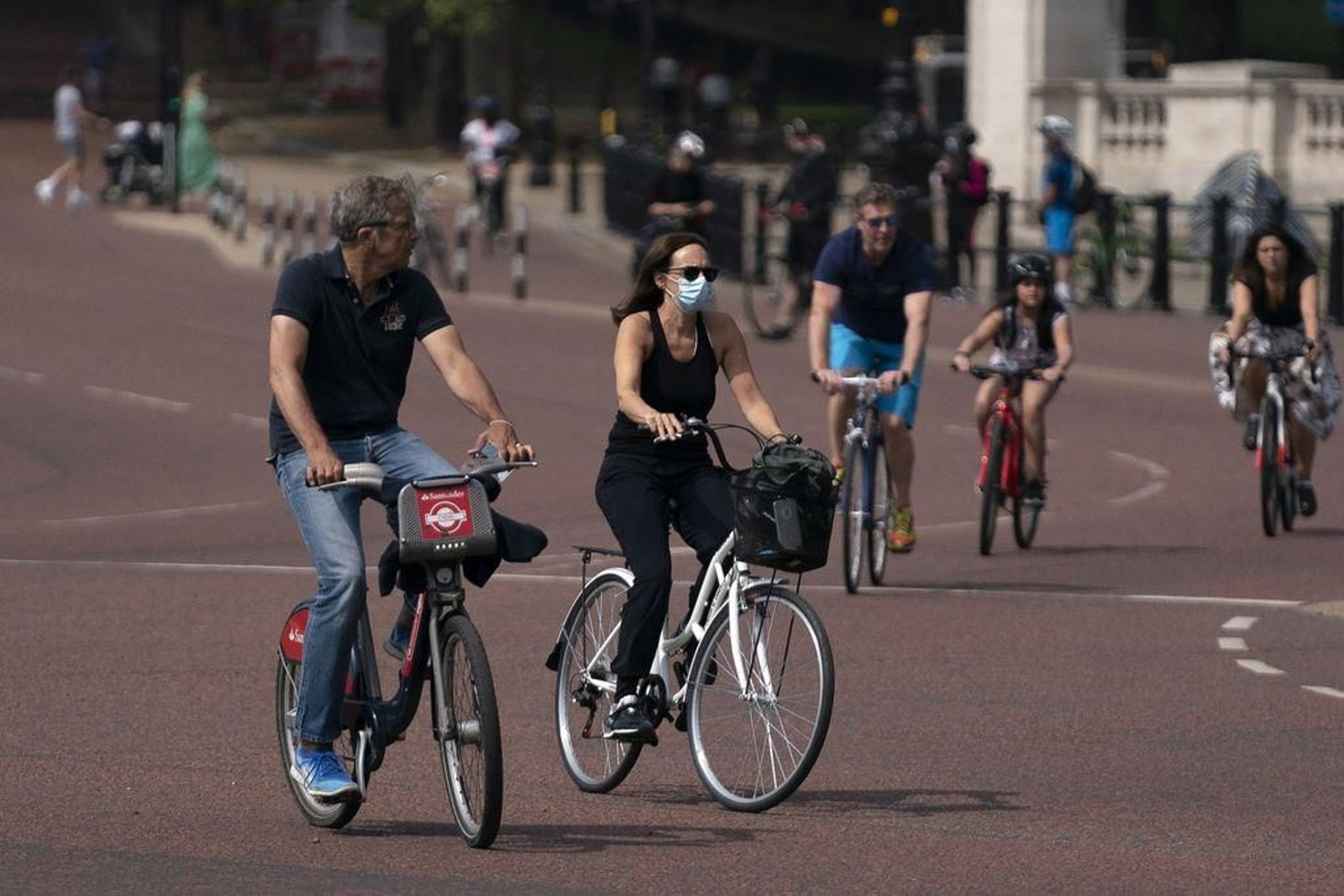 Un grupo de personas, solo con mascarilla, pasea en bicicleta por una calle de Londres.