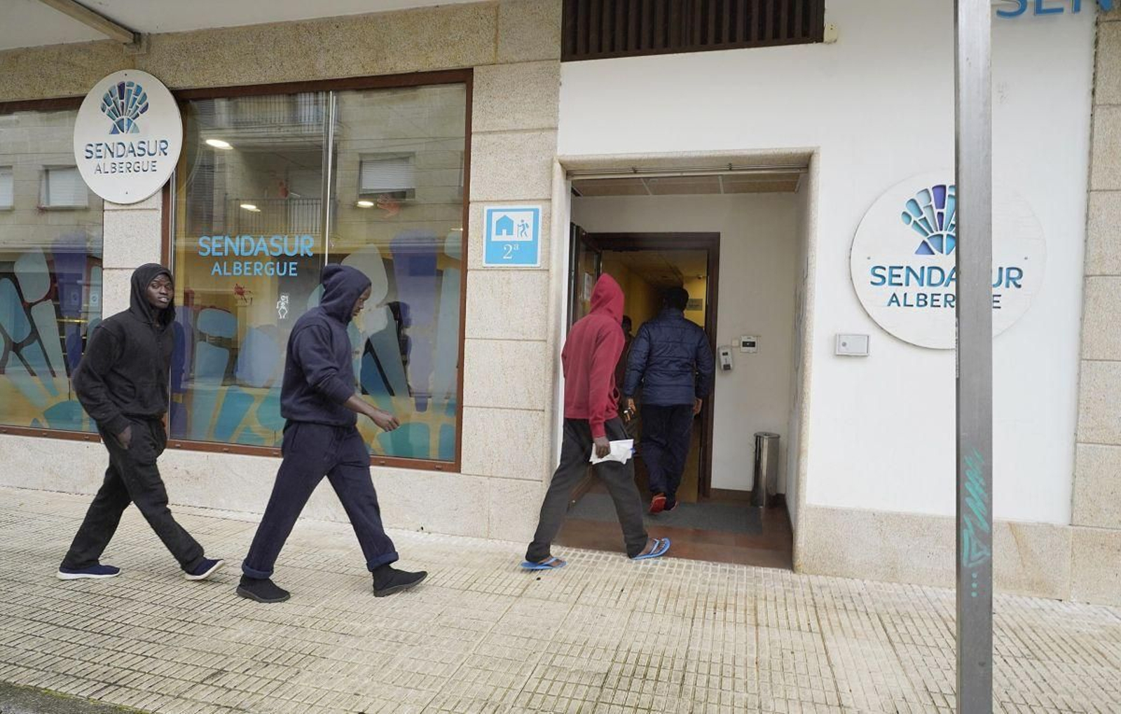 Algunos de los jóvenes inmigrantes senegaleses llegando ayer al hostal de Porriño.