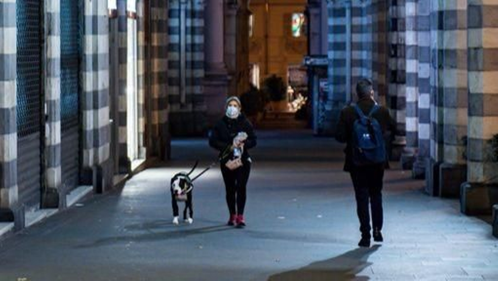 Dos personas pasean por el semi-vacío centro de Génova, Italia.