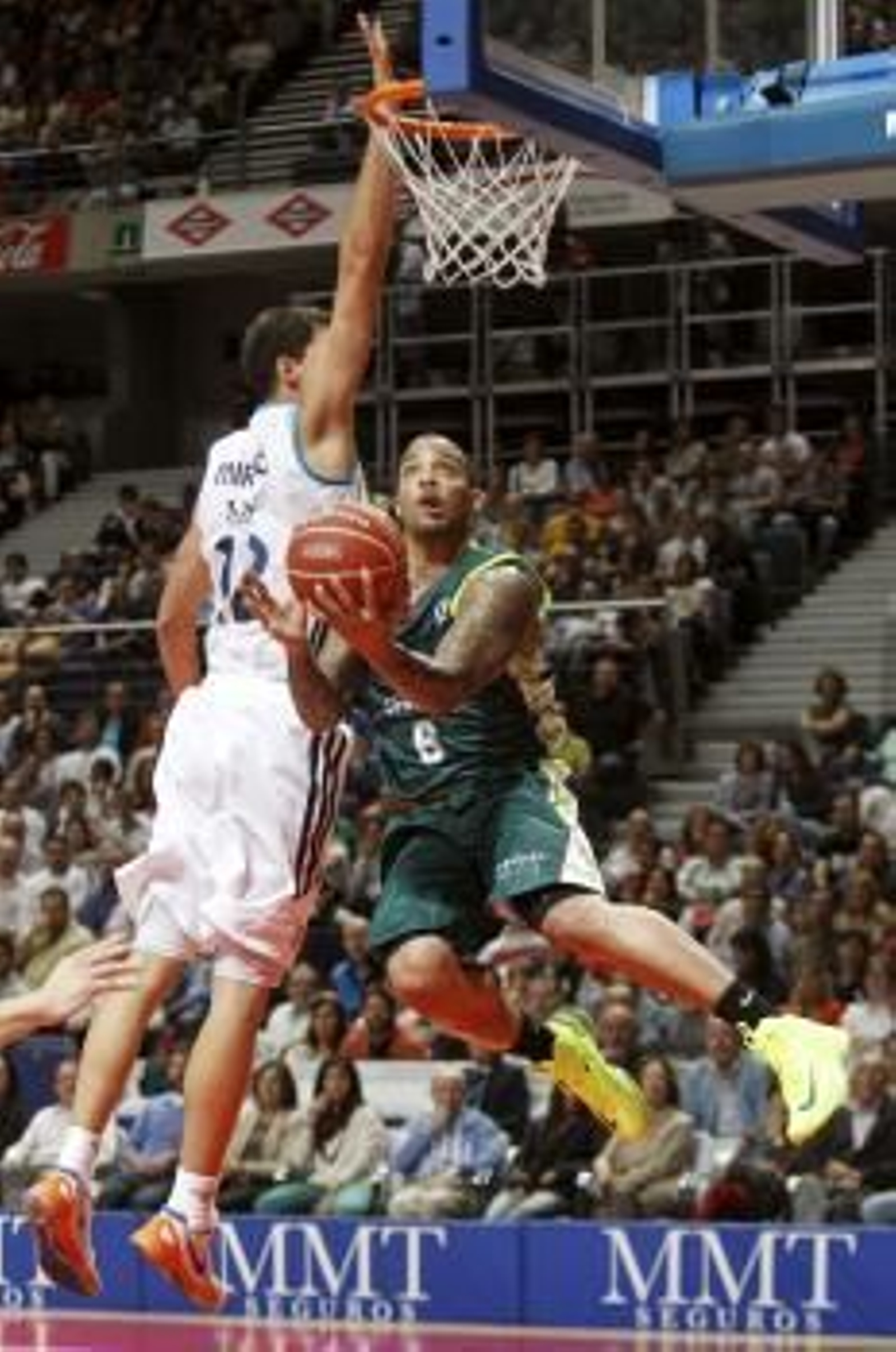 El ala-pívot del Real Madrid Nikola Mirotic (i) intenta taponar el lanzamiento del base estadounidense del Unicaja Marcus Williams (d) (Foto: EFE)