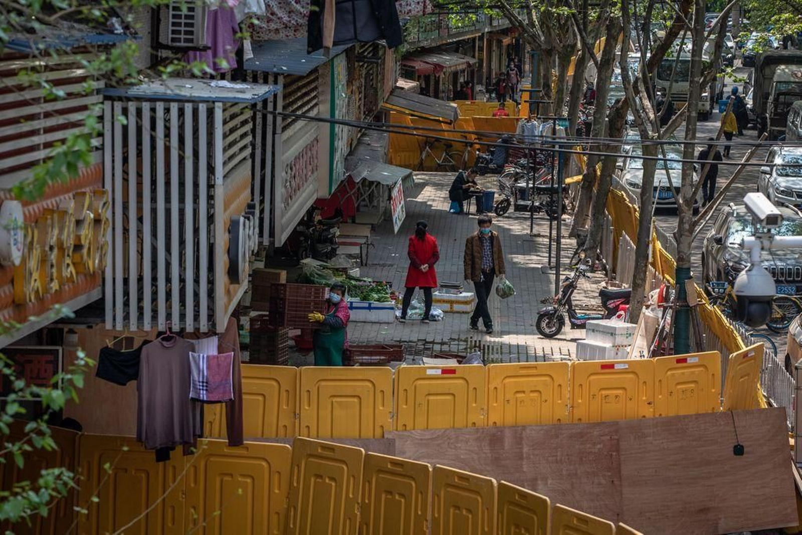 Varias personas se encuentran en el interior de un vallado mercado de Wuhan, centro de la pandemia.