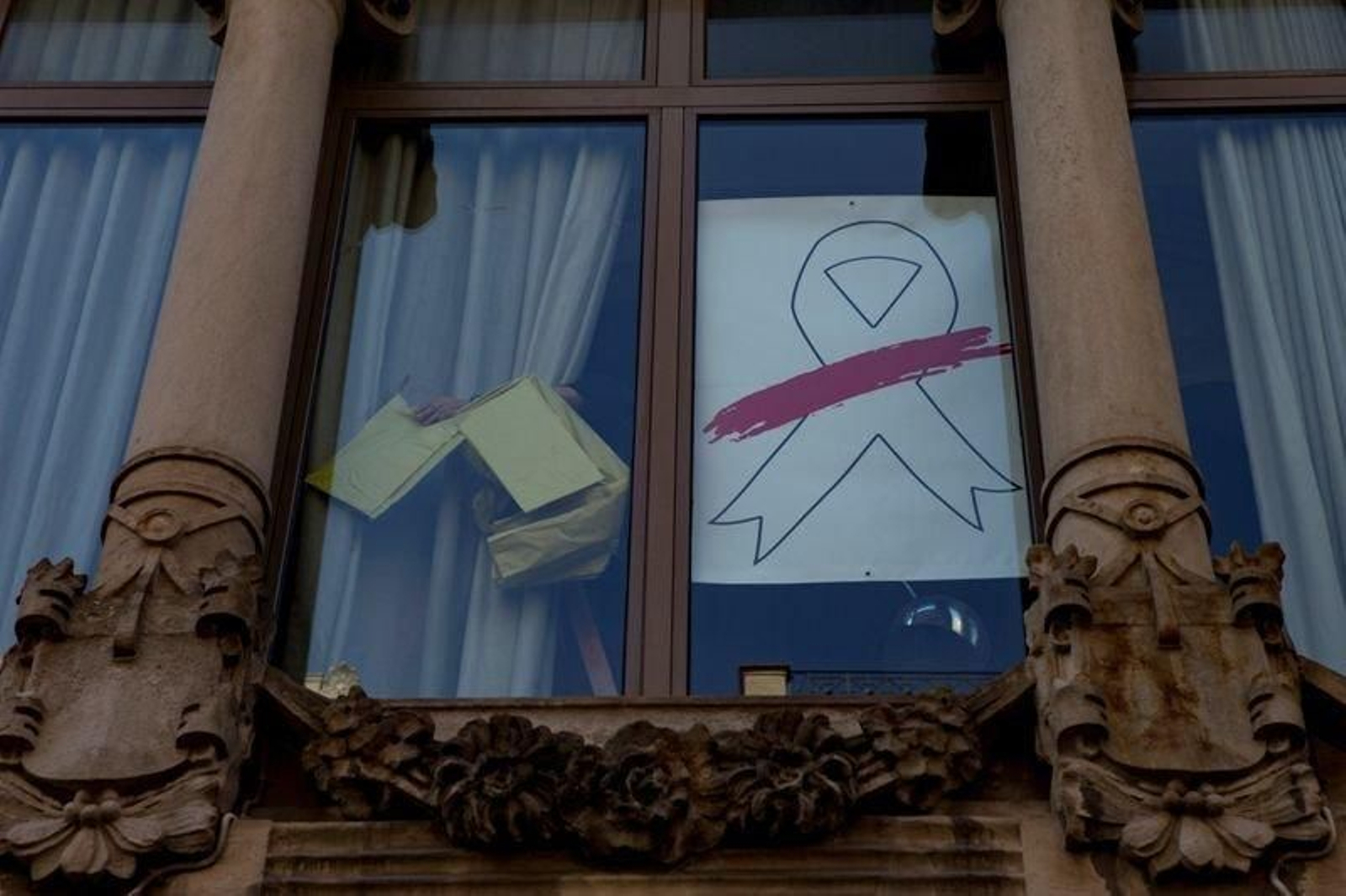 Un operario retira el lazo amarillo de la Consellería de Economía tras sustituirlo por otro de color blanco.