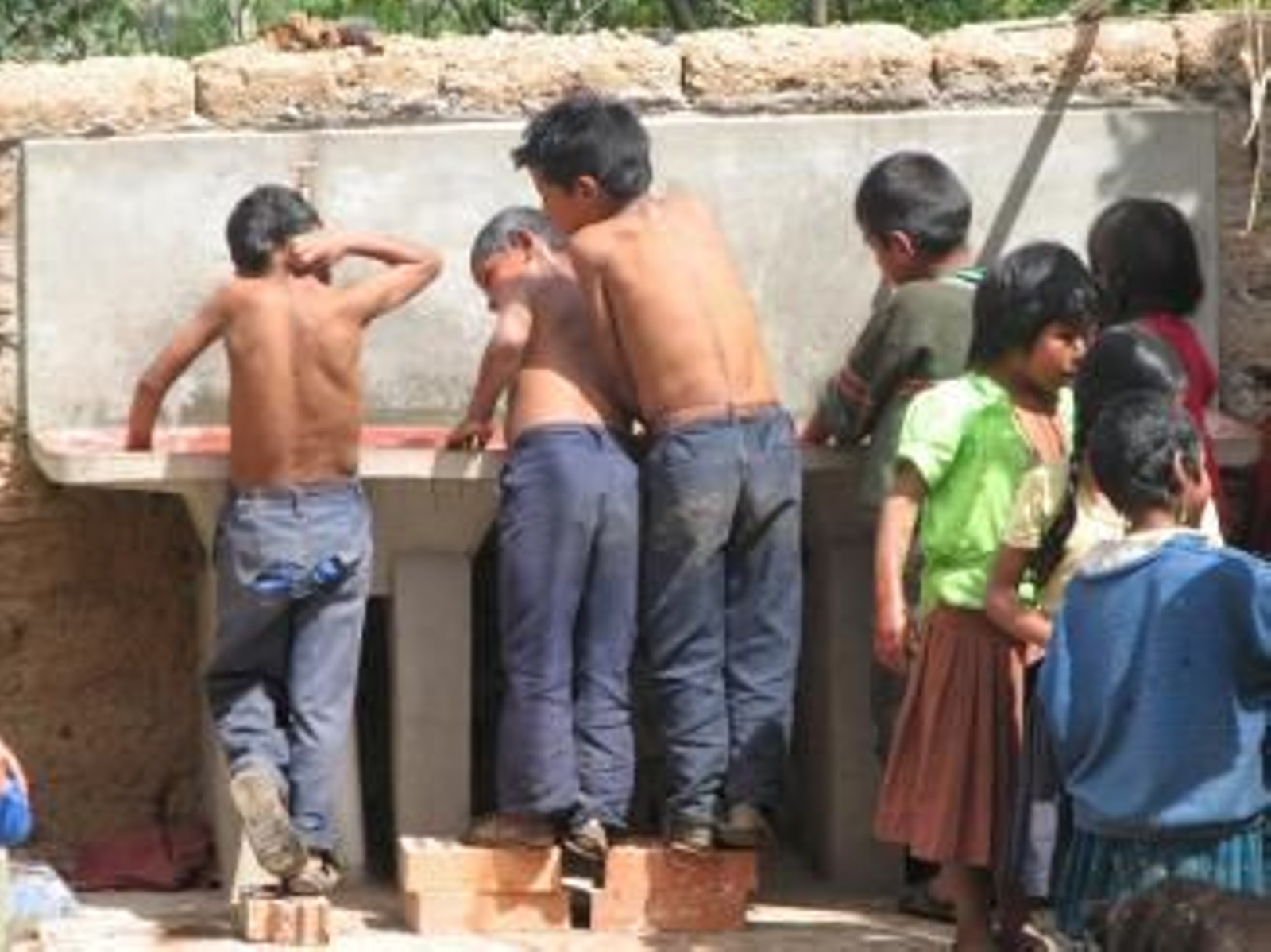 Un grupo de niños se lava en una de las piletas de un barrio chabolista