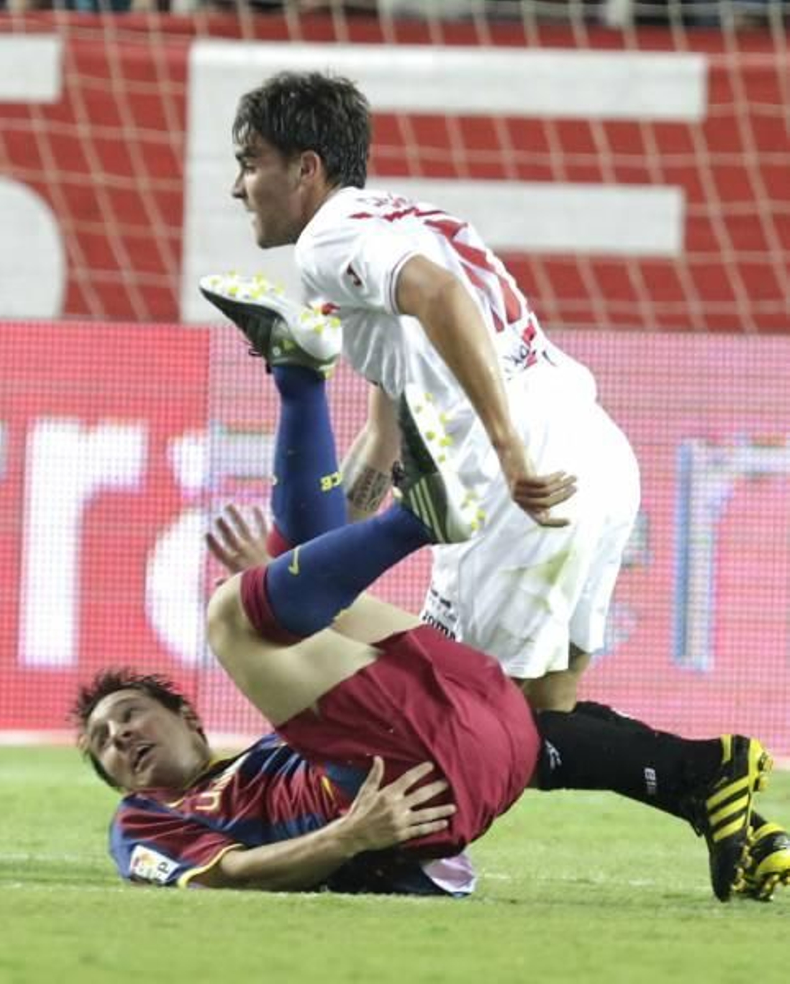 Messi cae a los pies del sevillista Cigarini durante el partido en el Sánchez Pizjuán. EFE