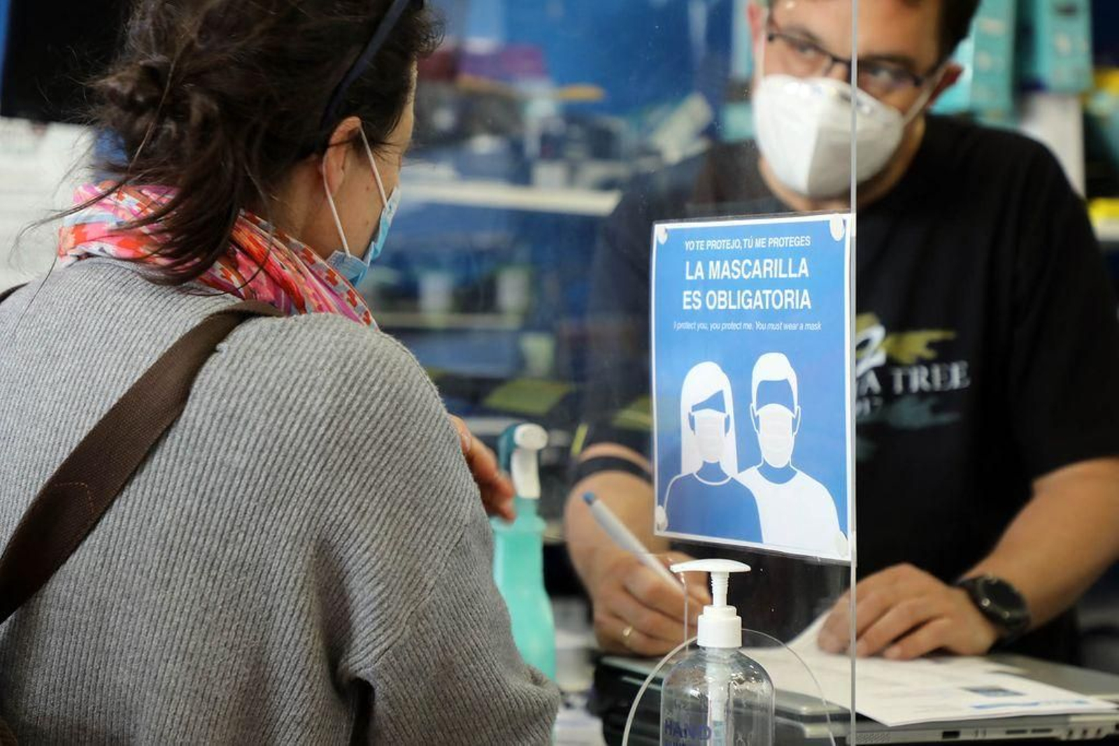 Un dependiente atiende a una clienta bajo las medidas de prevención.