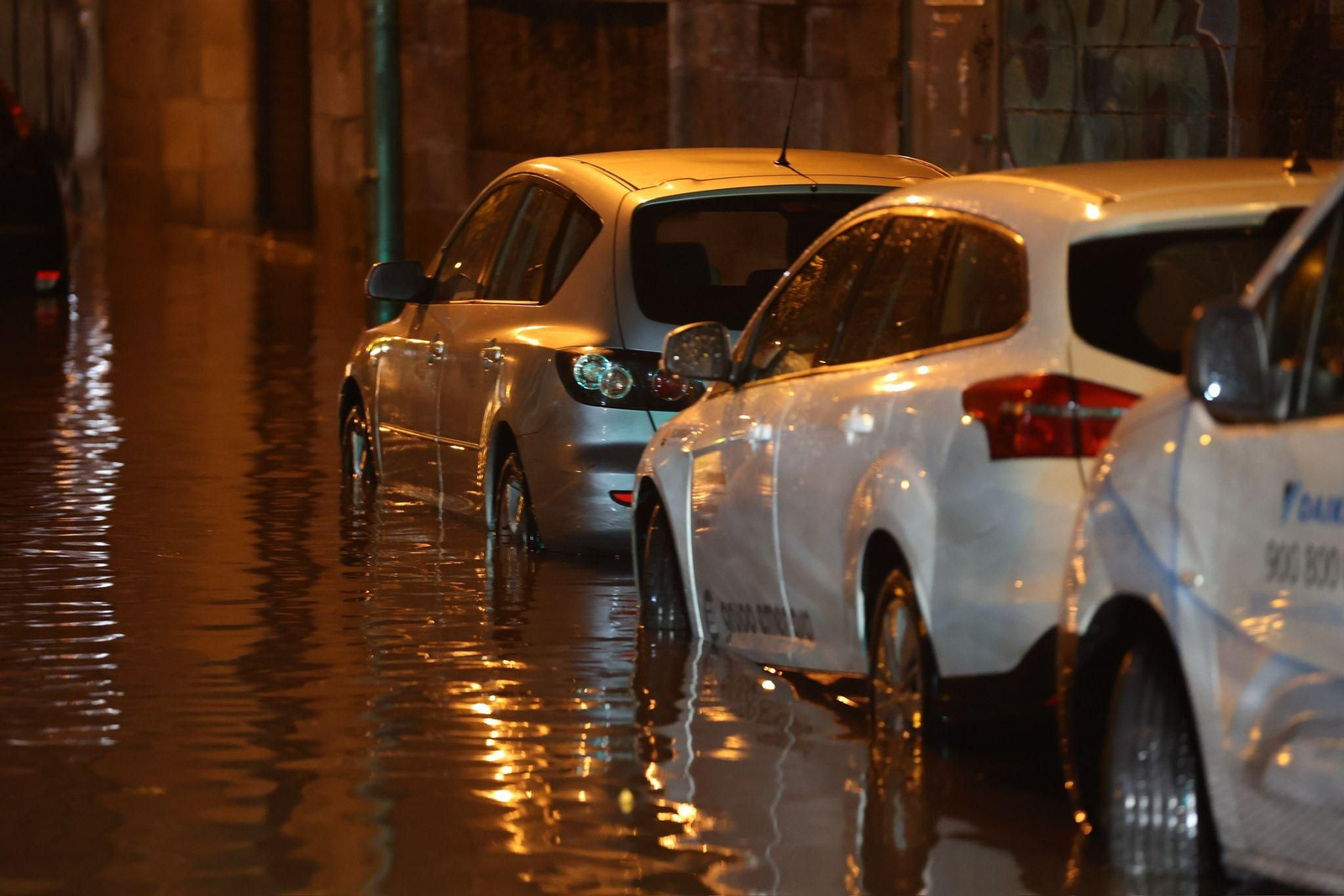 La altura del agua llega por las ruedas de varios coches estacionados en la calle.