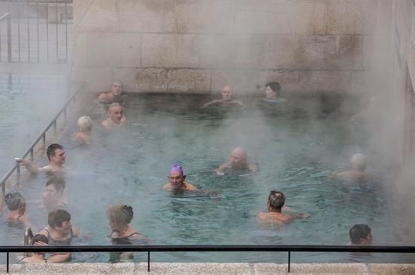 Varias personas se bañan en la piscina termal de As Burgas, pese a las bajas temperaturas registradas hoy en la ciudad.