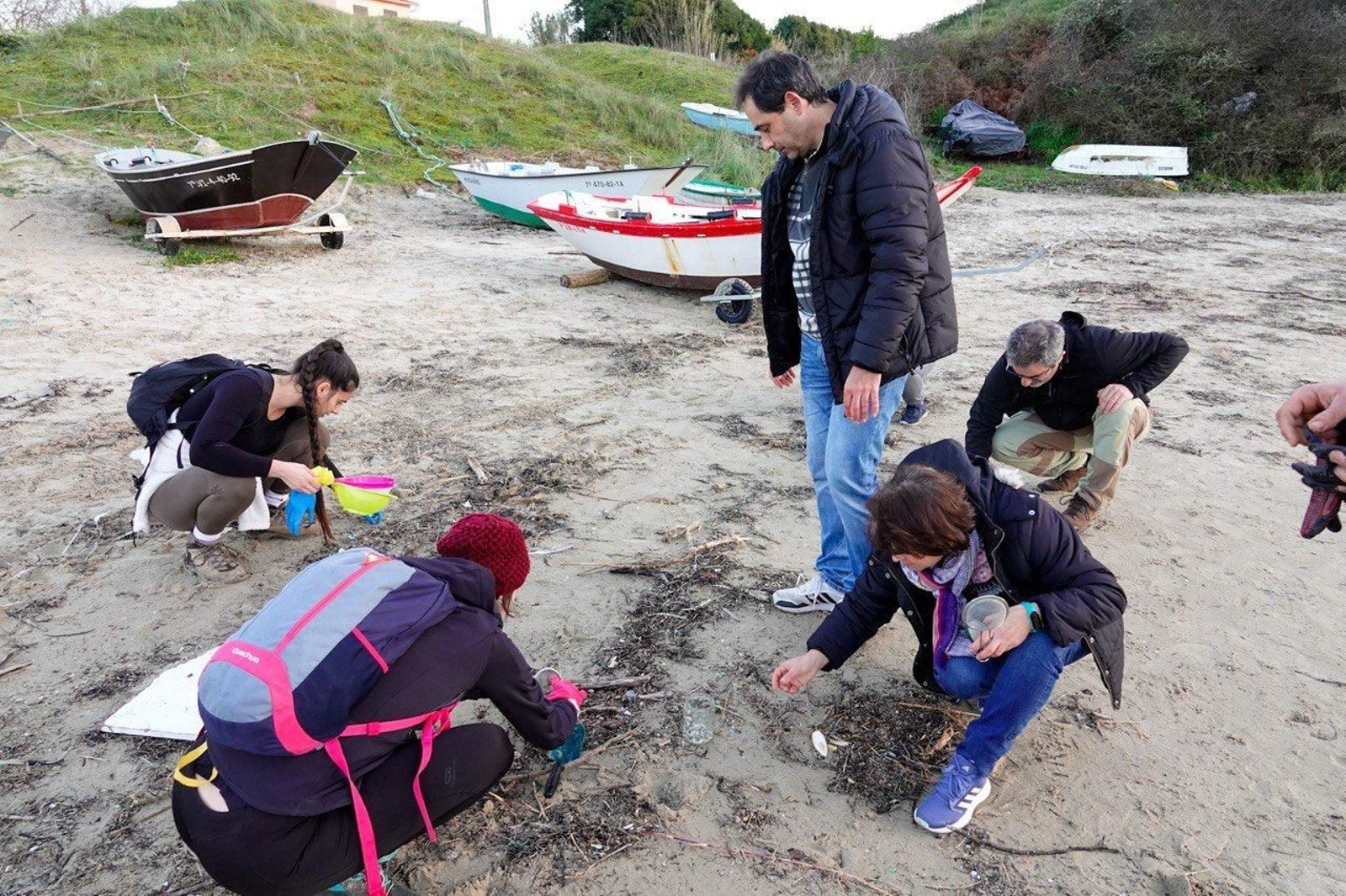 Voluntarios recogen pellets de plástico.