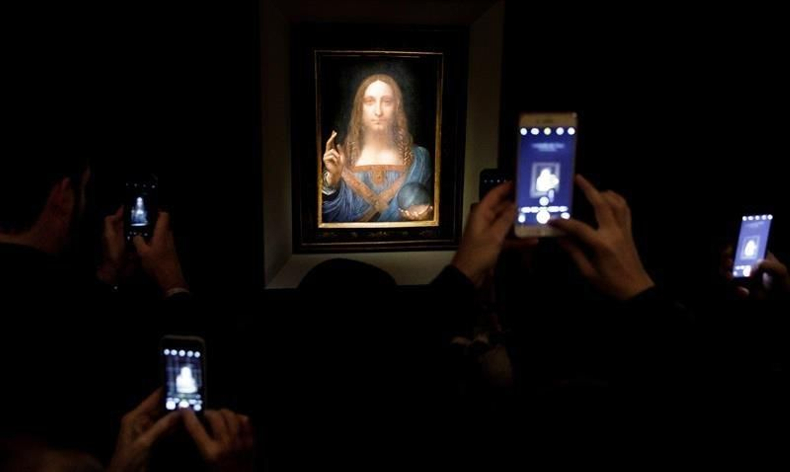 Varias personas fotografían la obra 'Salvator Mundi' del artista Leonardo da Vinci (1500)