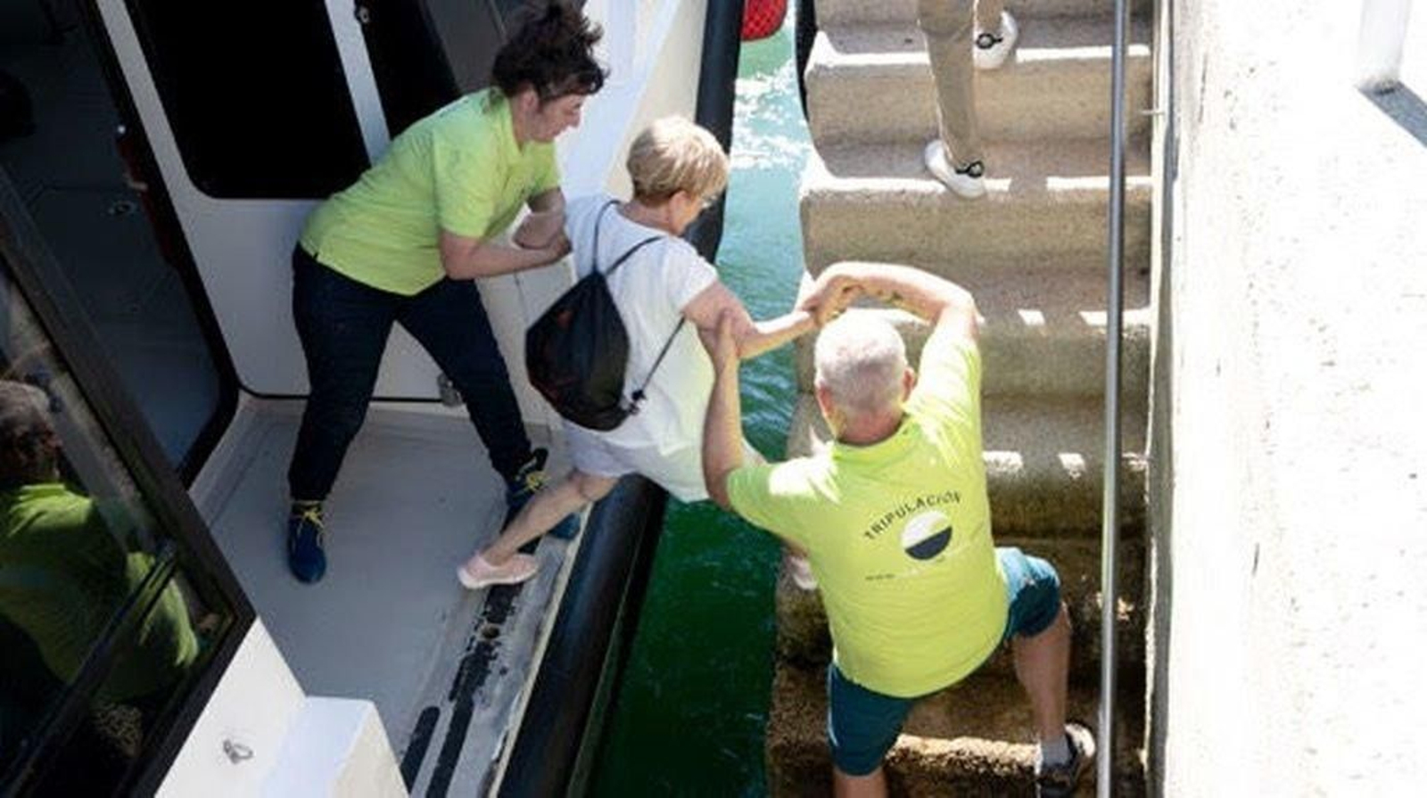 Tripulantes de Nabia ayudan a una pasajera en el muelle de Cangas.