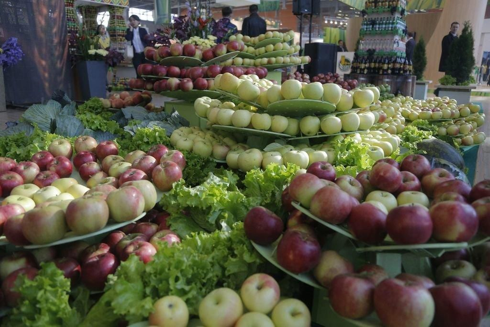 Manzanas y lechugas en las estanterías de frutería de un supermercado.