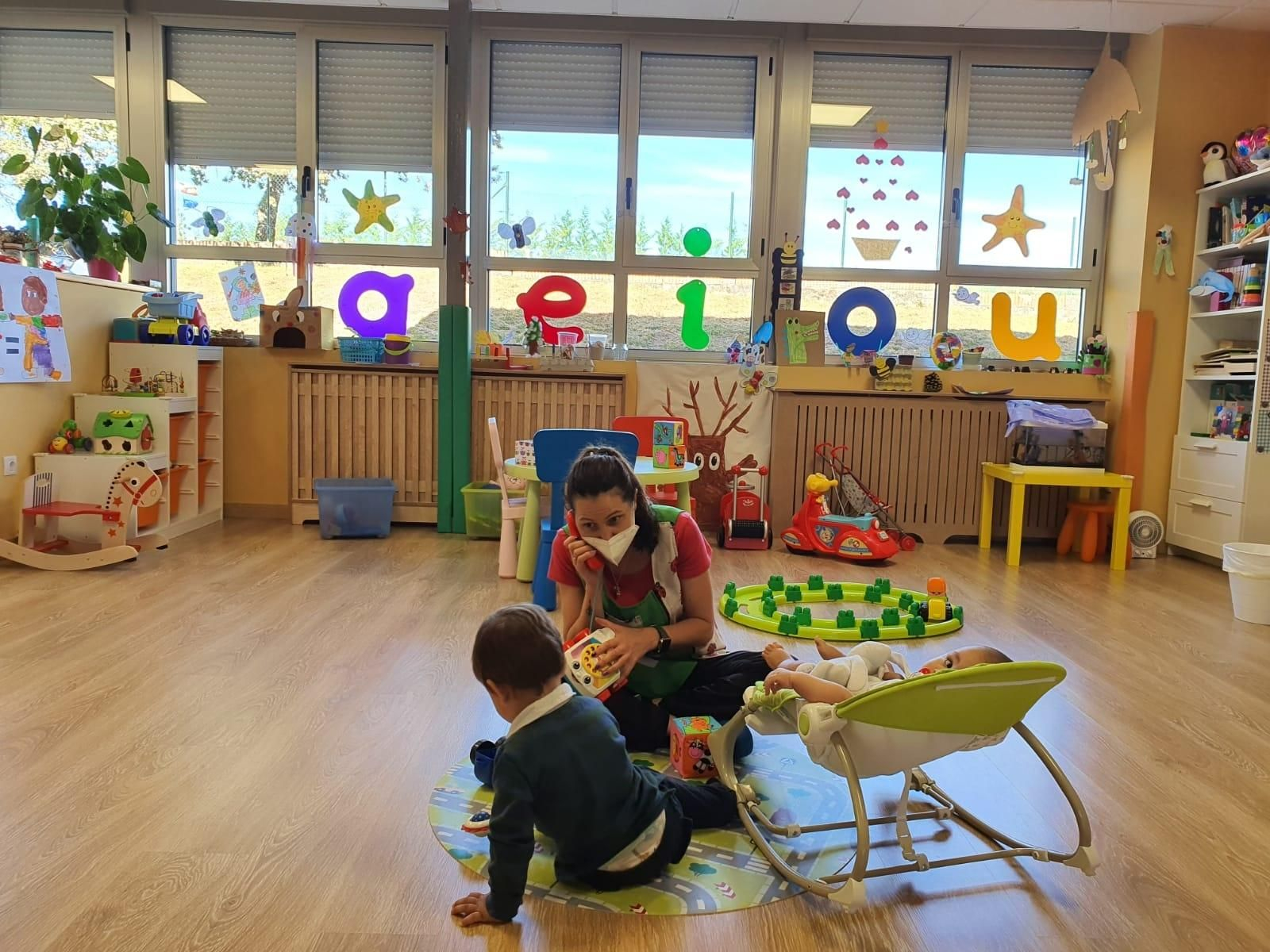 Beatriz Millán con un bebé y un niño, jugando en su Casa Niño de Beariz.