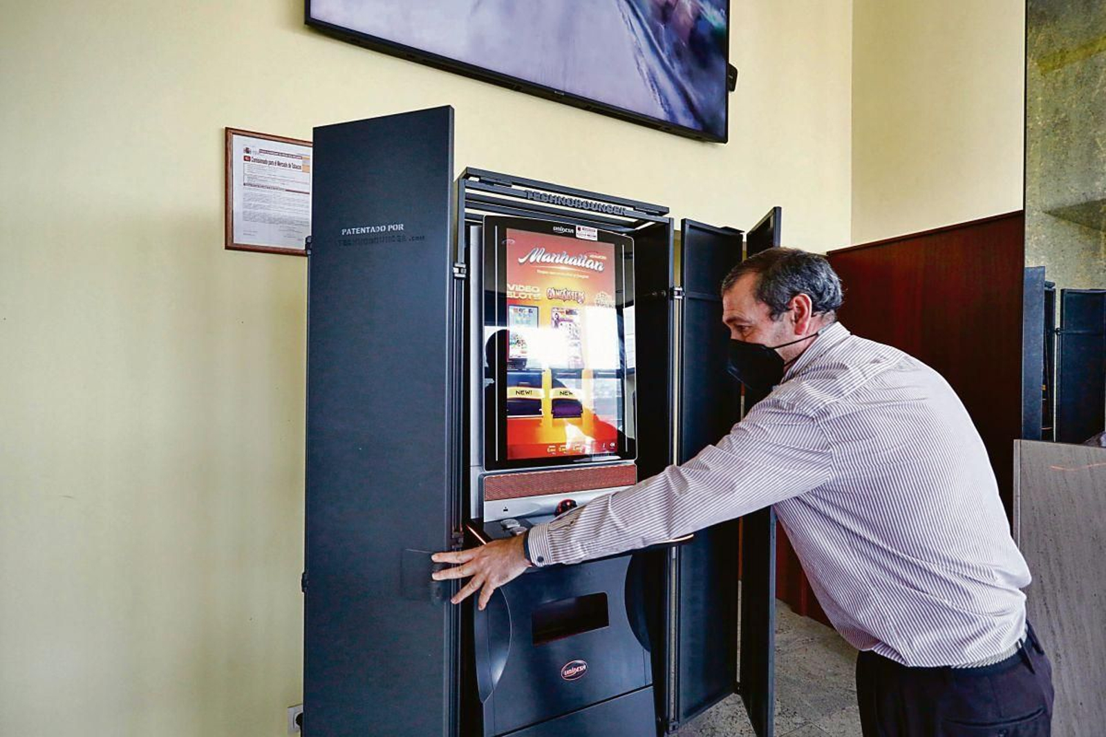 Ramón, propietario de un local en Beade recientemente asaltado, muestra la jaula acorazada que protege la máquina tragaperras.