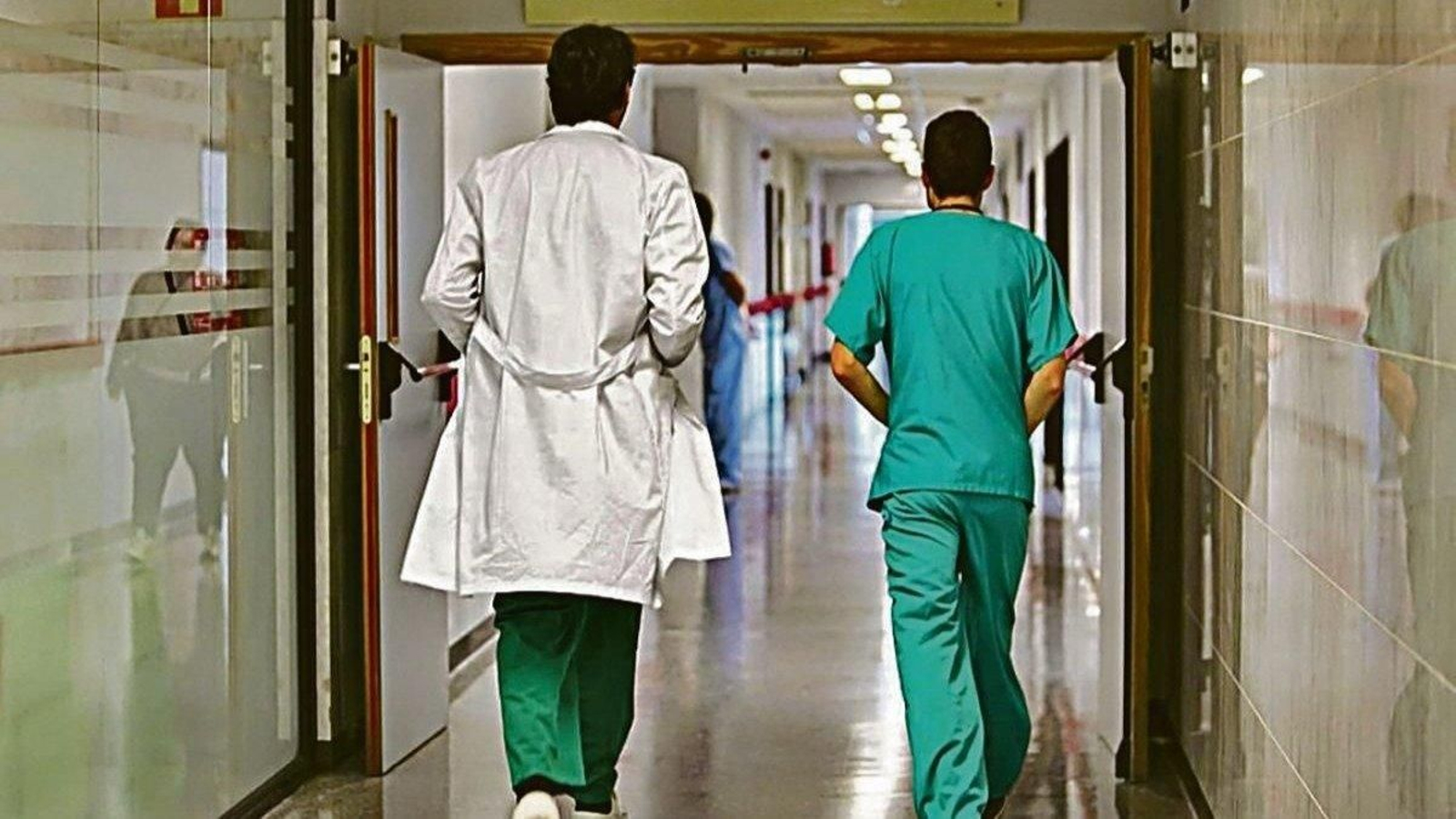 Un médico acude a consulta en un hospital acompañado por un residente.