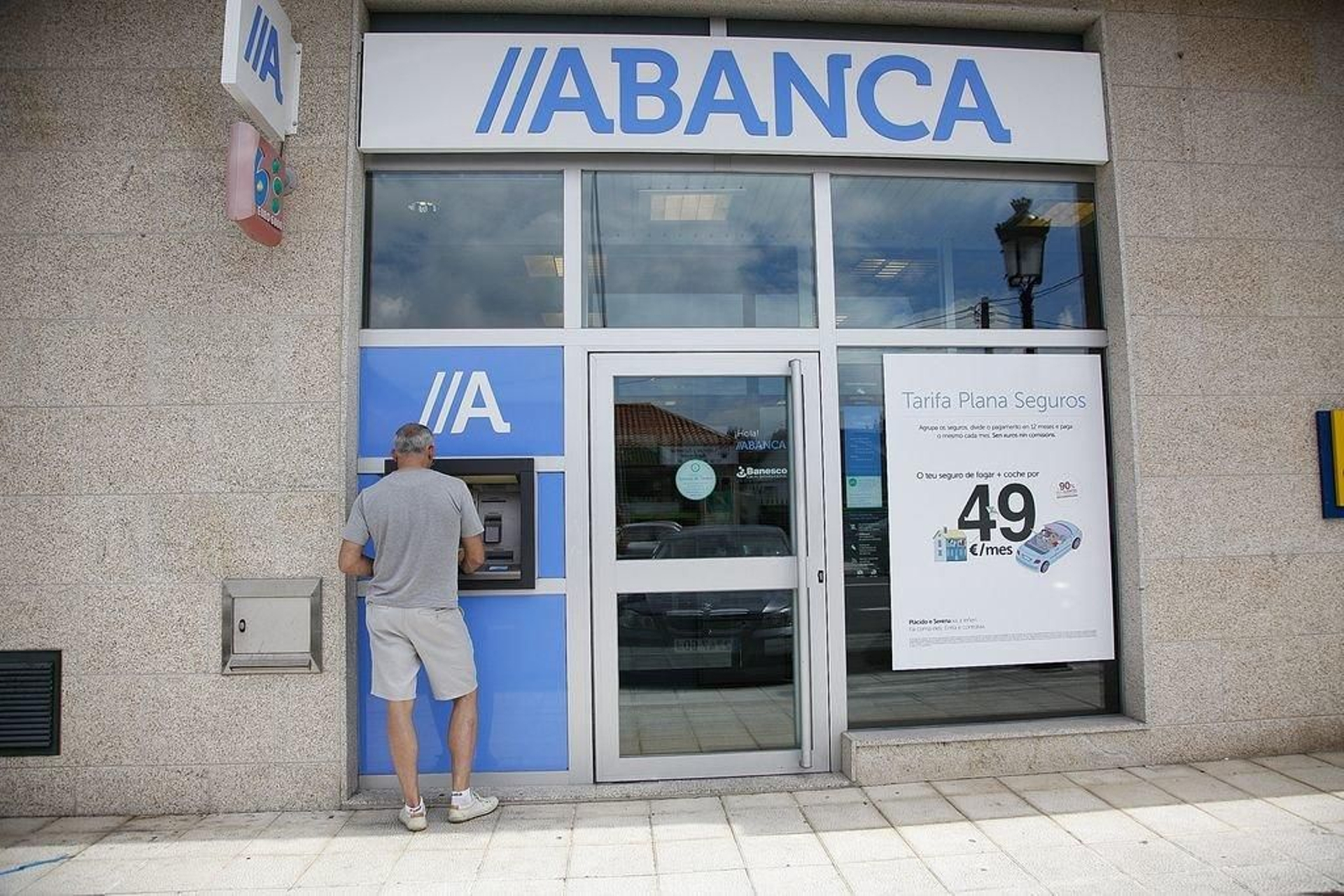 Una persona retira dinero de un cajero automático en una sucursal rural de Abanca.