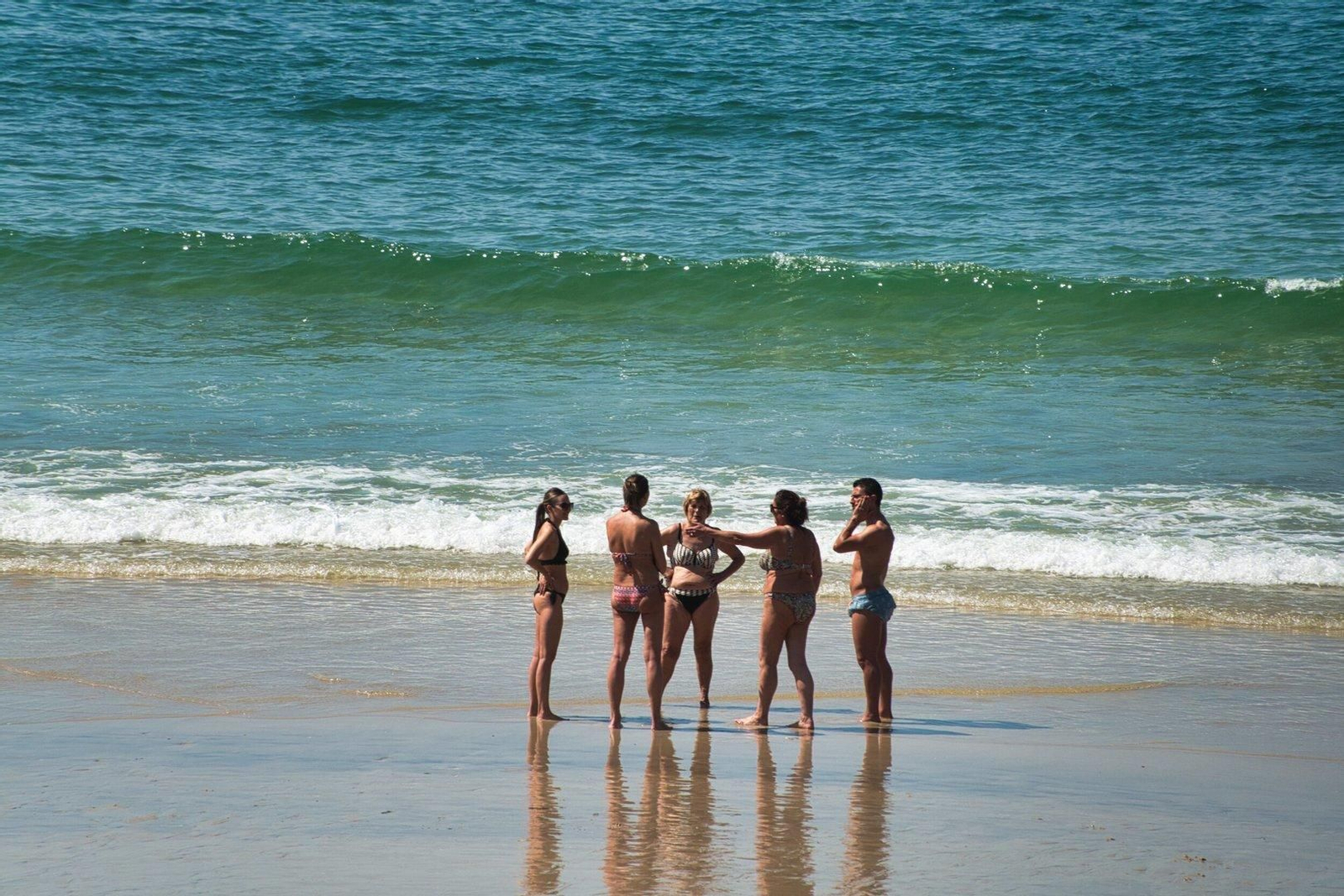 Grupo de gente hablando a la orilla en Samil.