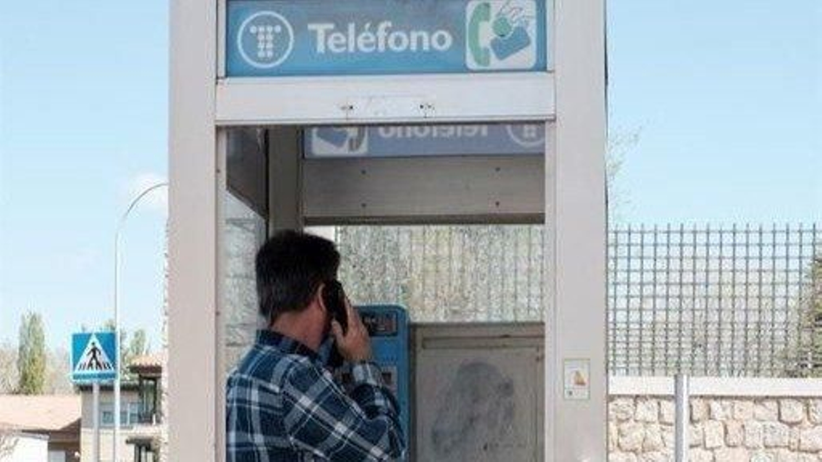 Un joven utiliza una vieja cabina instalada en la calle.