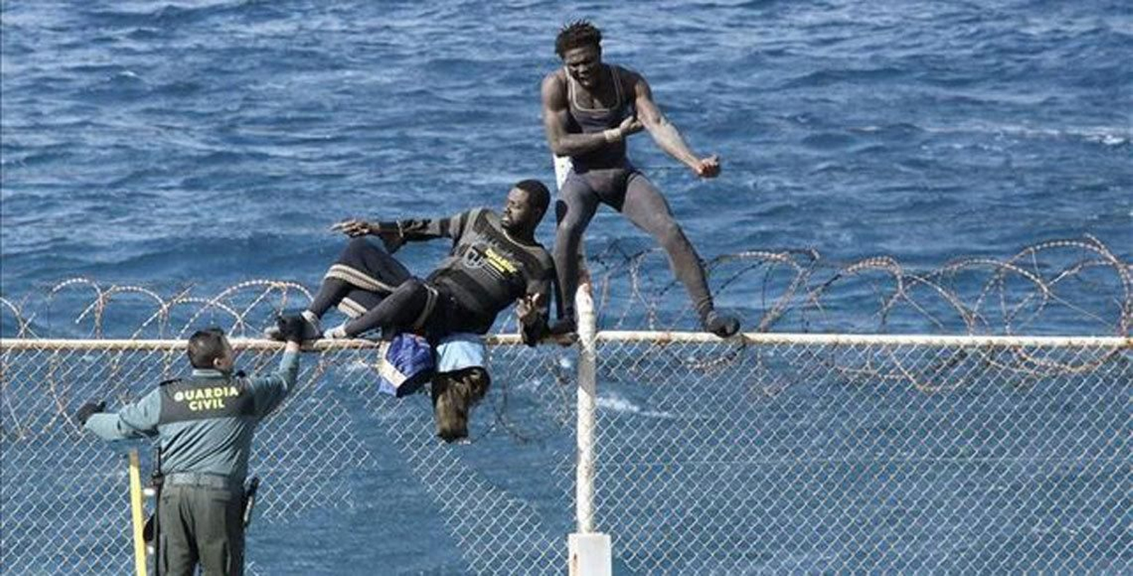 Dos inmigrantes subsaharianos intentan saltar la valla de Ceuta.