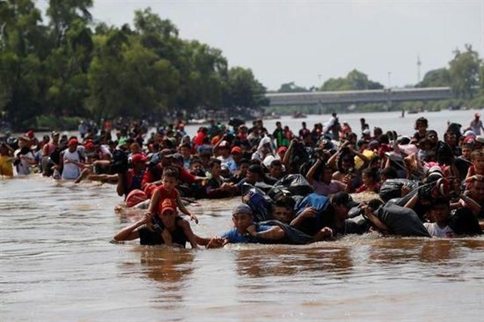 Integrantes de la caravana de migrantes cruzan a pie el río Suchiate por una parte que no es muy profunda y que separa a Guatemala de México.