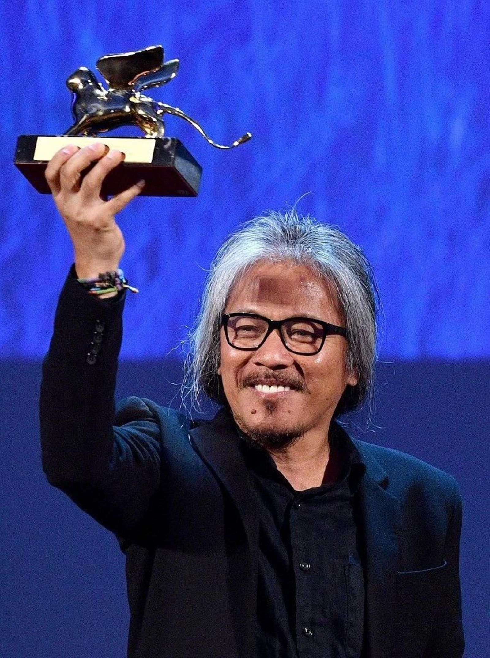 Lav Diaz celebra el premio en el escenario de la Mostra.