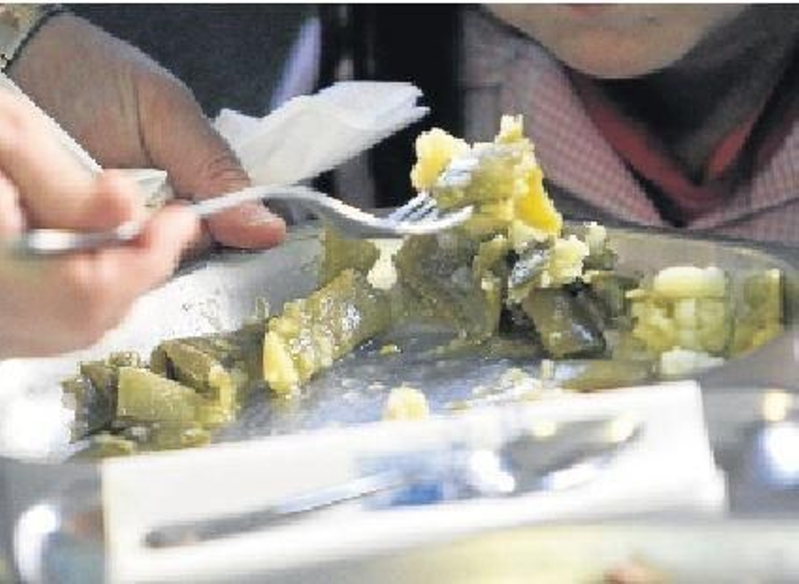 Una monitora da de comer verdura a una niña en un comedor escolar