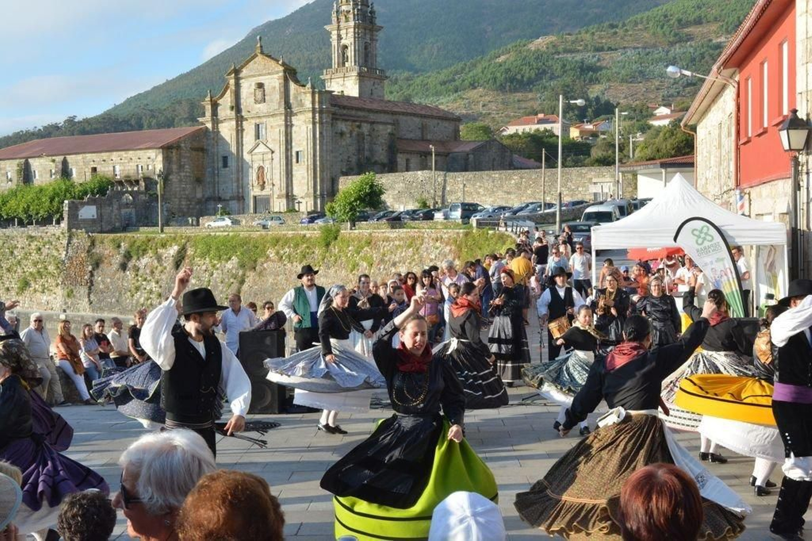 Celebración de la XXVI fiesta Encontro dos Pobos con el monasterio de fondo.
