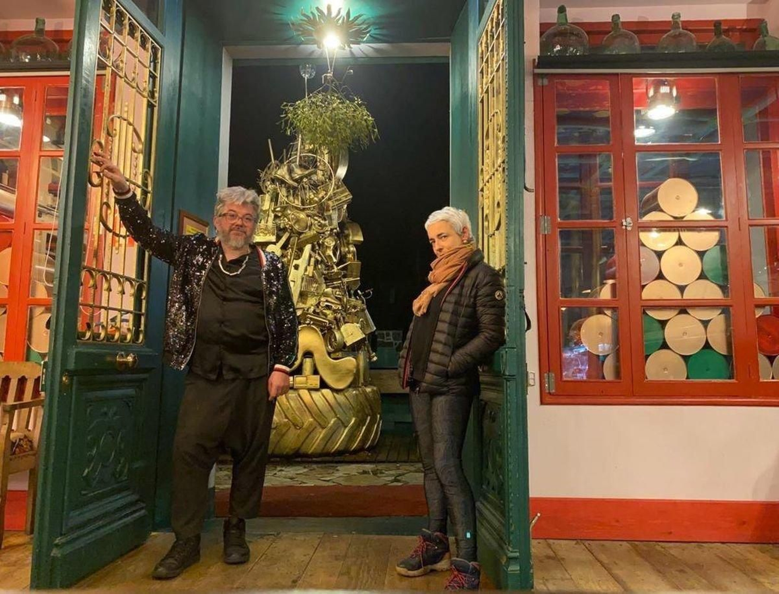 Rubén González y su socia Natalia Restrepo, con el árbol de chatarra detrás.