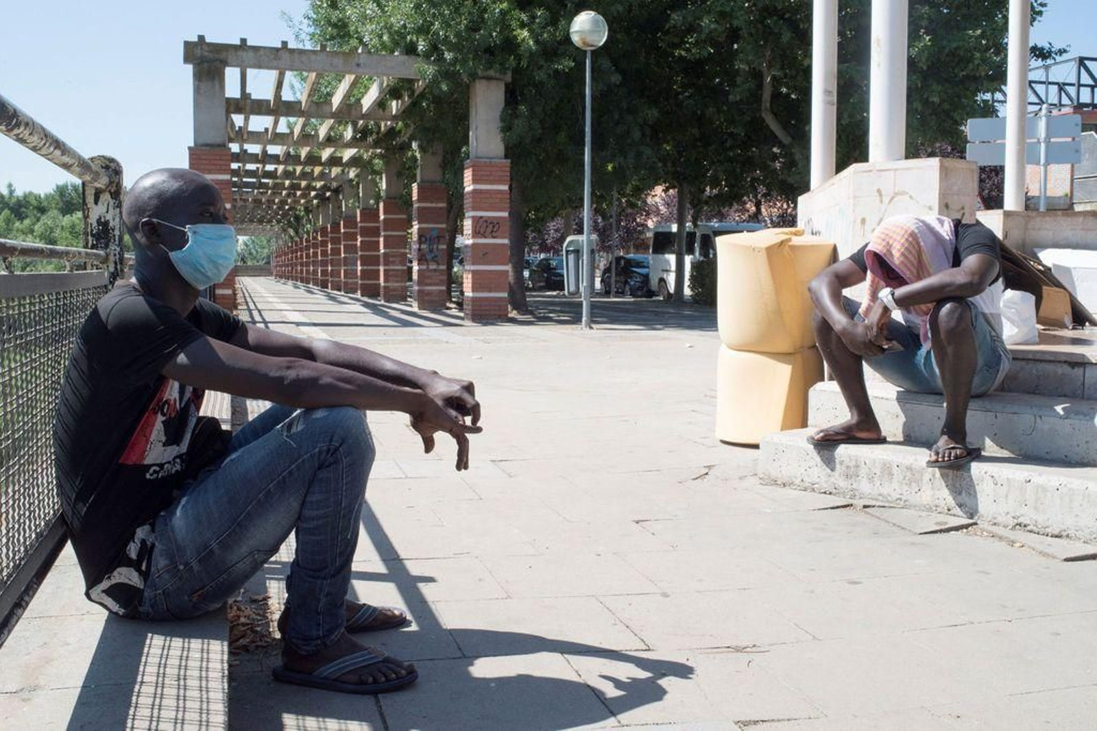 Dos inmigrantes, sentados en la calle de Fraga, llevan días sin trabajar debido al brote de coronavirus.