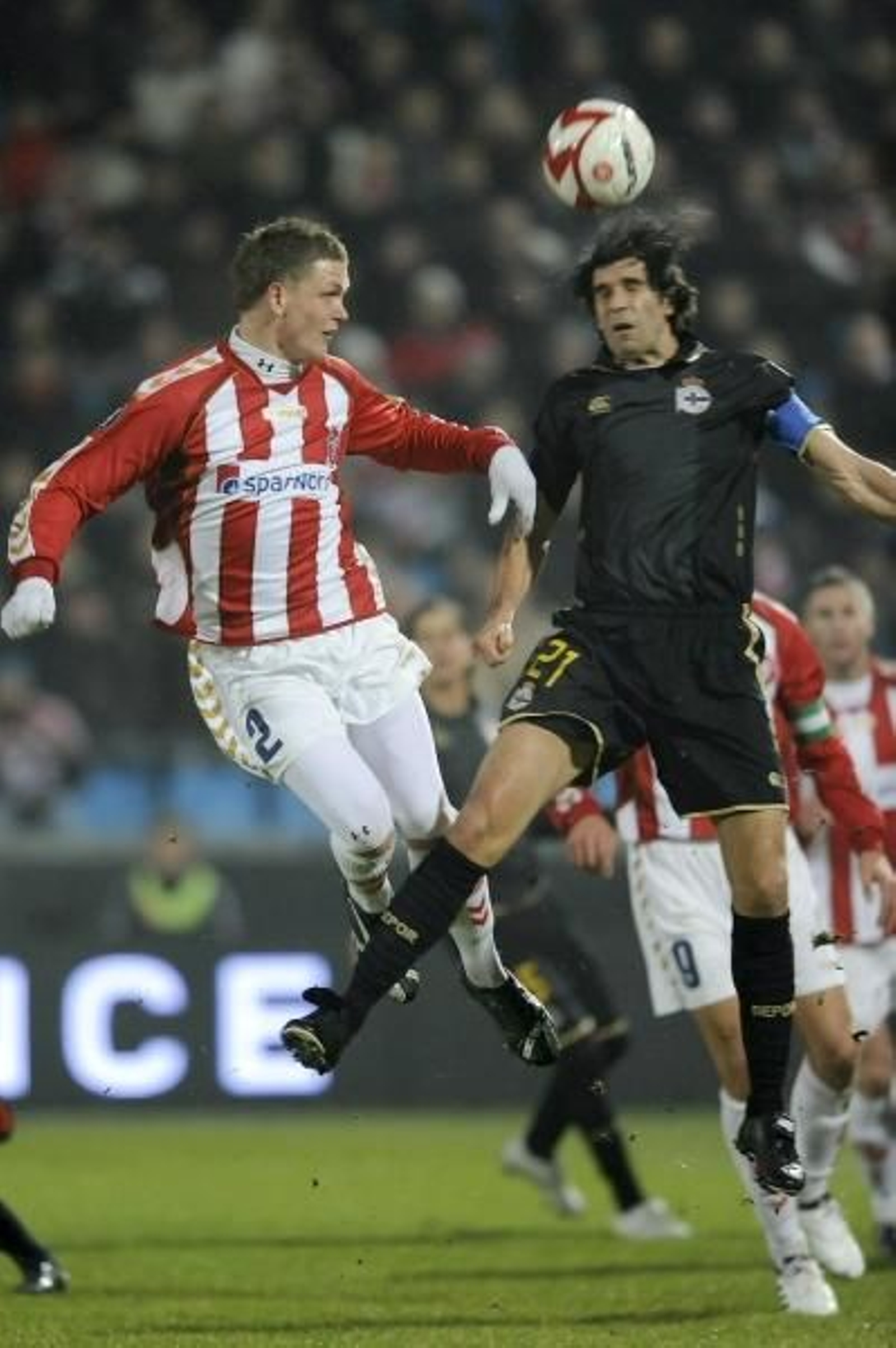 Juan Carlos Valerón salta a por un balón con un defensa del Aalborg. (Foto: EFE)