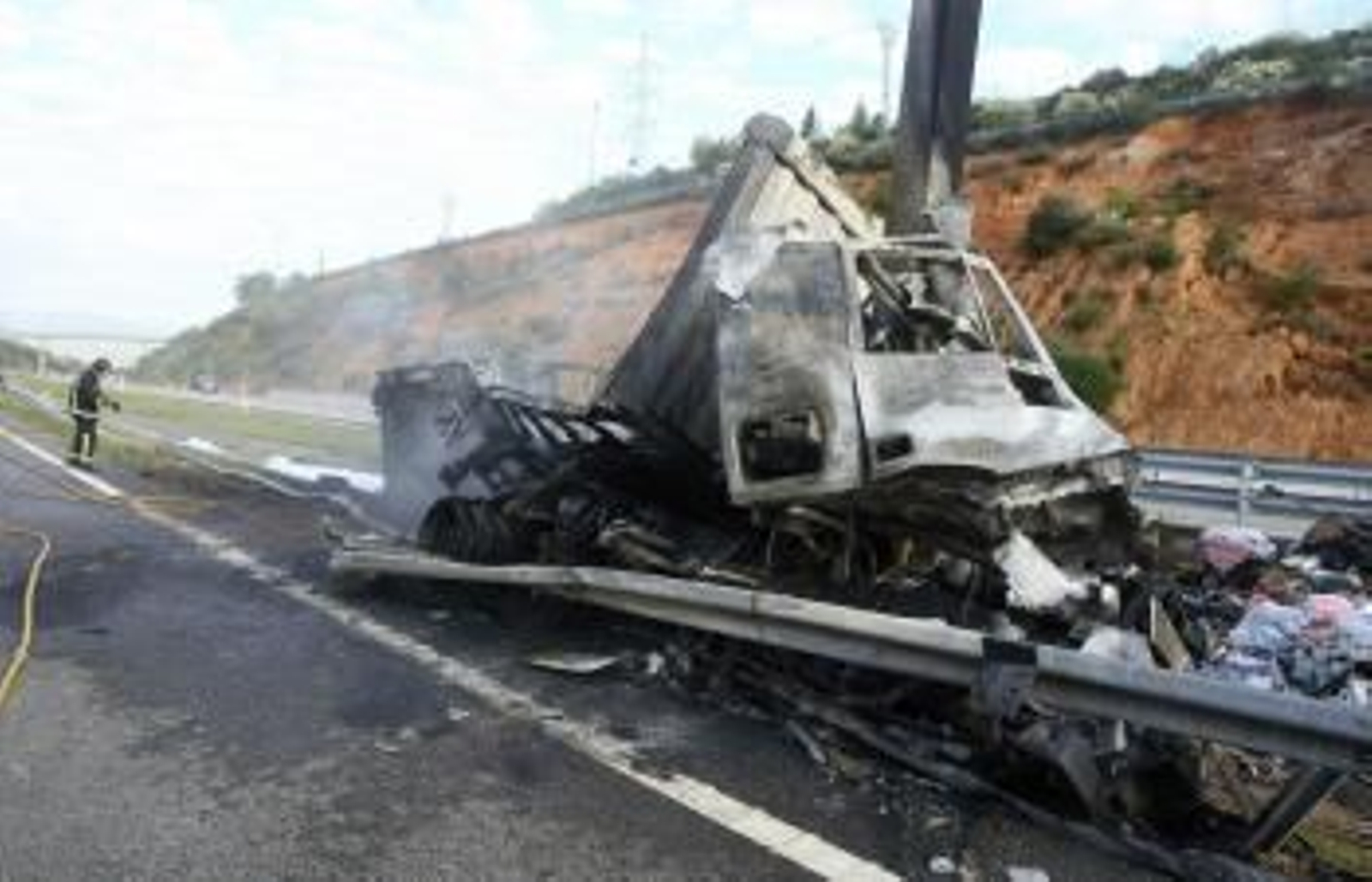 Imagen del estado en el que ha quedado el camión que esta madrugada se ha incendiado tras salirse de la vía en la autopista del Noroeste A-6.