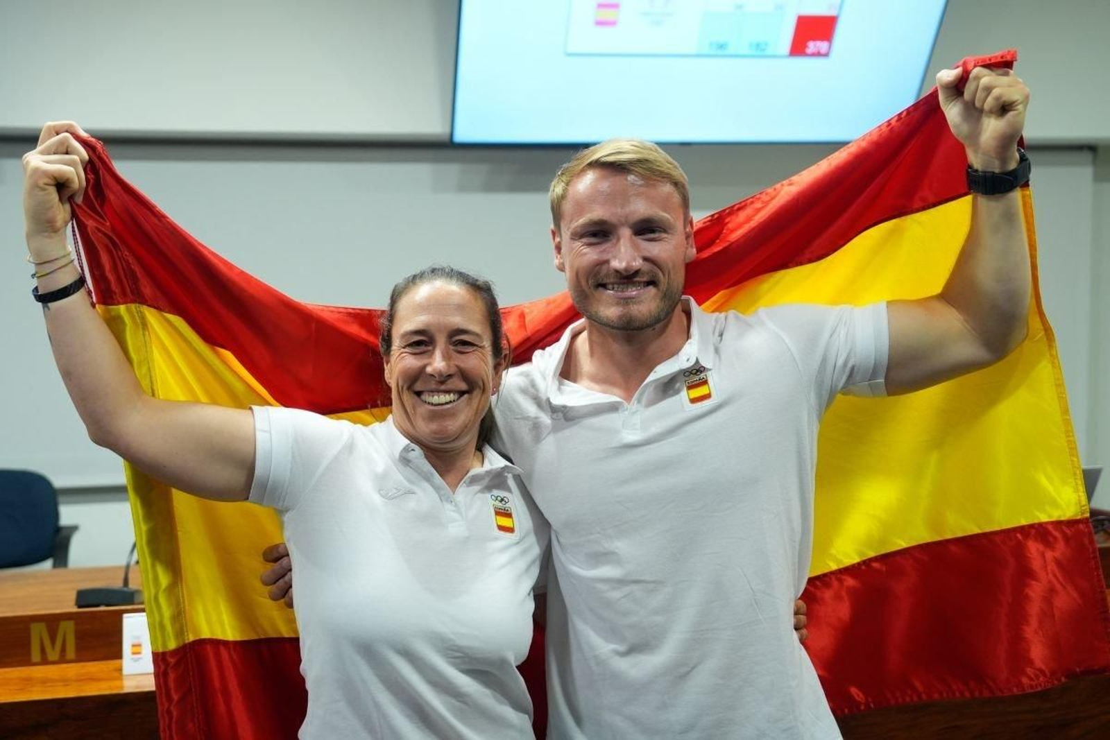 Támara Echegoyen y Marcus Cooper, con la bandera española tras ser designados oficialmente como los abanderados para París.