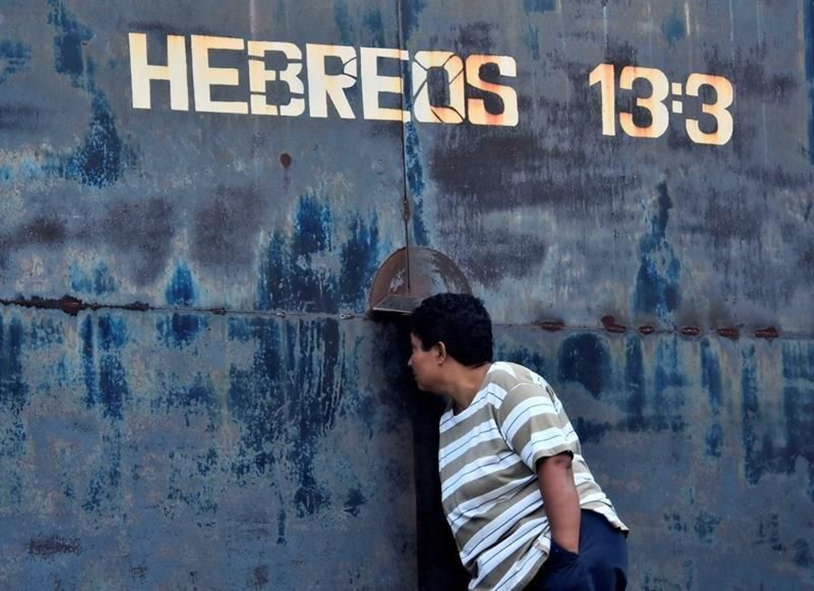 Una mujer observa por una rendija en una puerta del centro penitenciario de Tela,  en el municipio de Atlántida (Honduras)