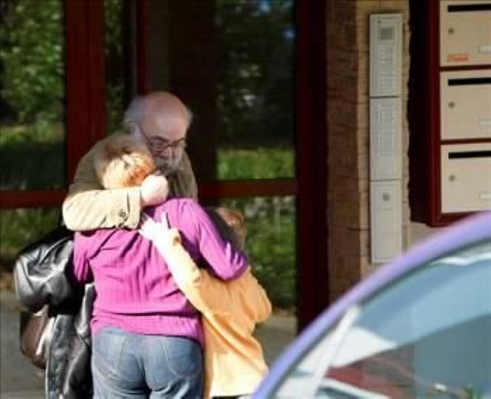 El padre de David Pla, el presunto etarra detenido esta madrugada en la localidad fronteriza de Hendaya, se abraza a una mujer y un niño a las puertas del domicilio donde se produjo el arresto. (Foto: JAVIER ETXEZARRETA)