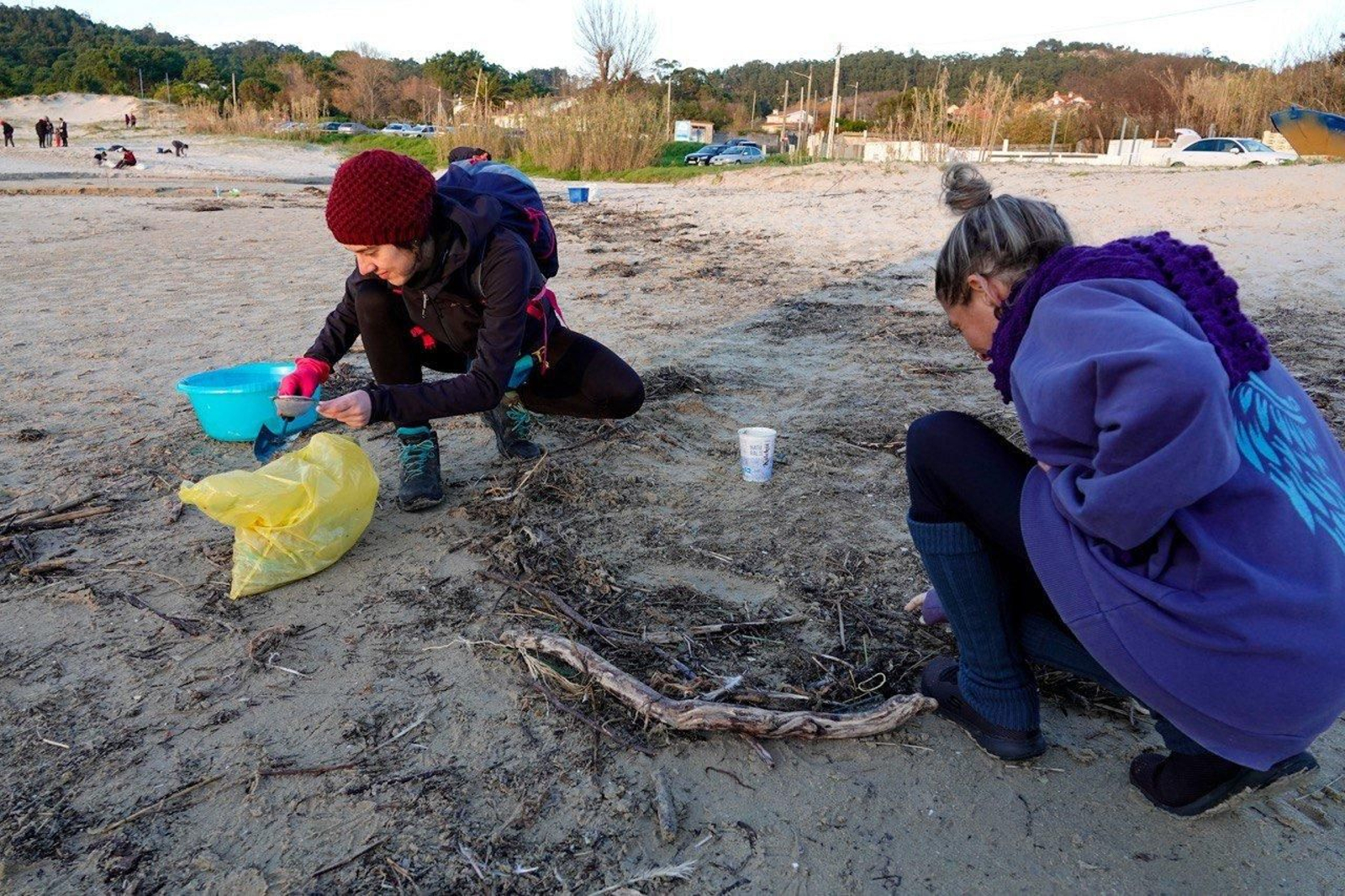 Voluntarios recogen pellets de plástico.