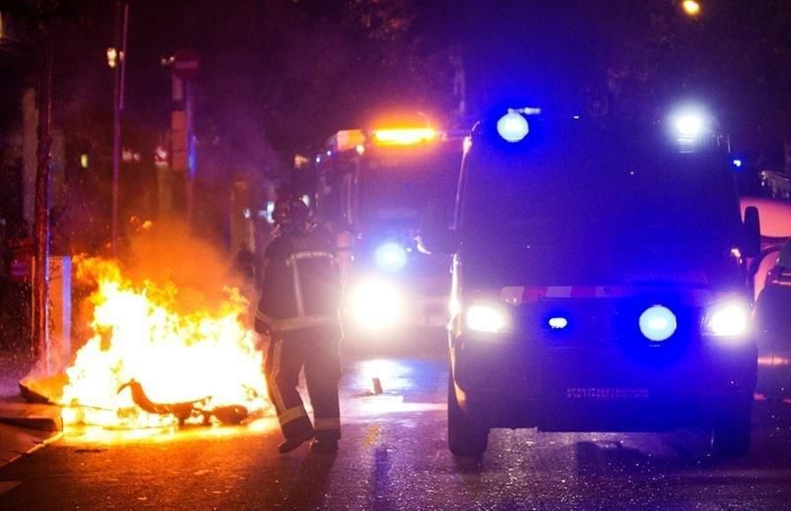 Un contenedor ardiendo y los bomberos intentando extinguirlo.