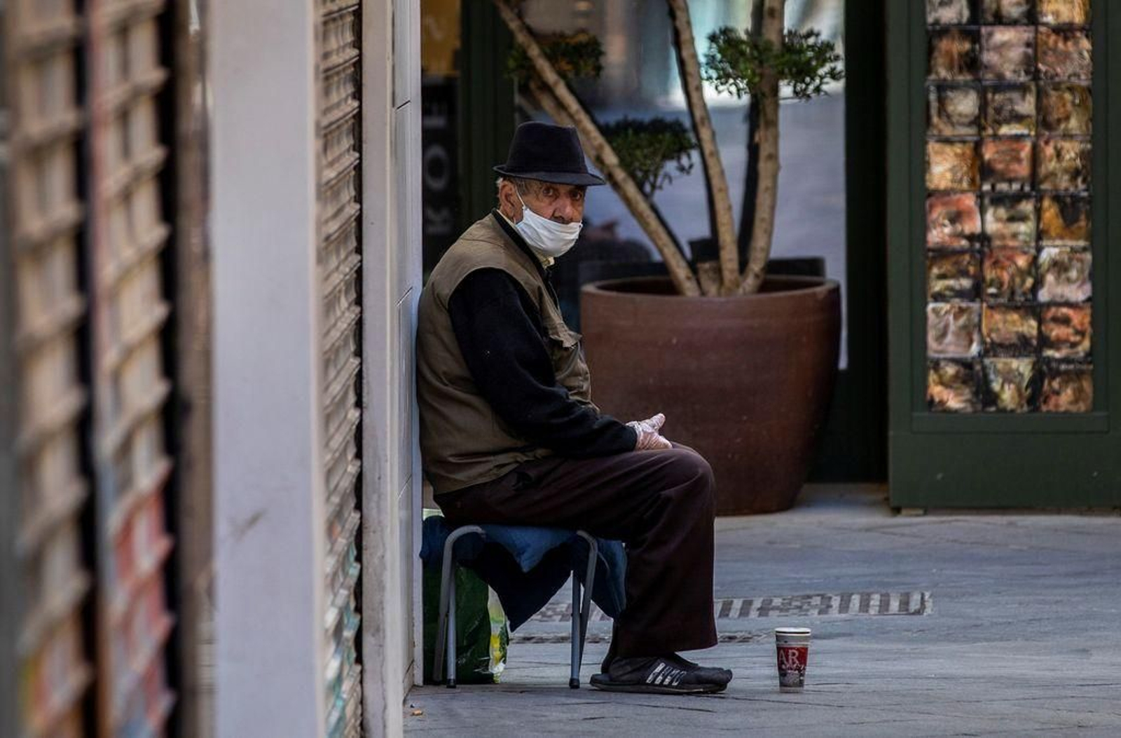 Un hombre protegido con mascarilla y guantes pide limosna en una céntrica calle de Sevilla.