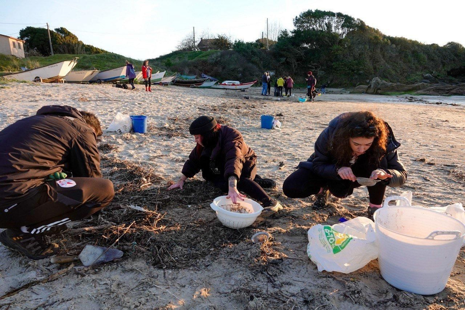 Voluntarios recogen pellets de plástico.