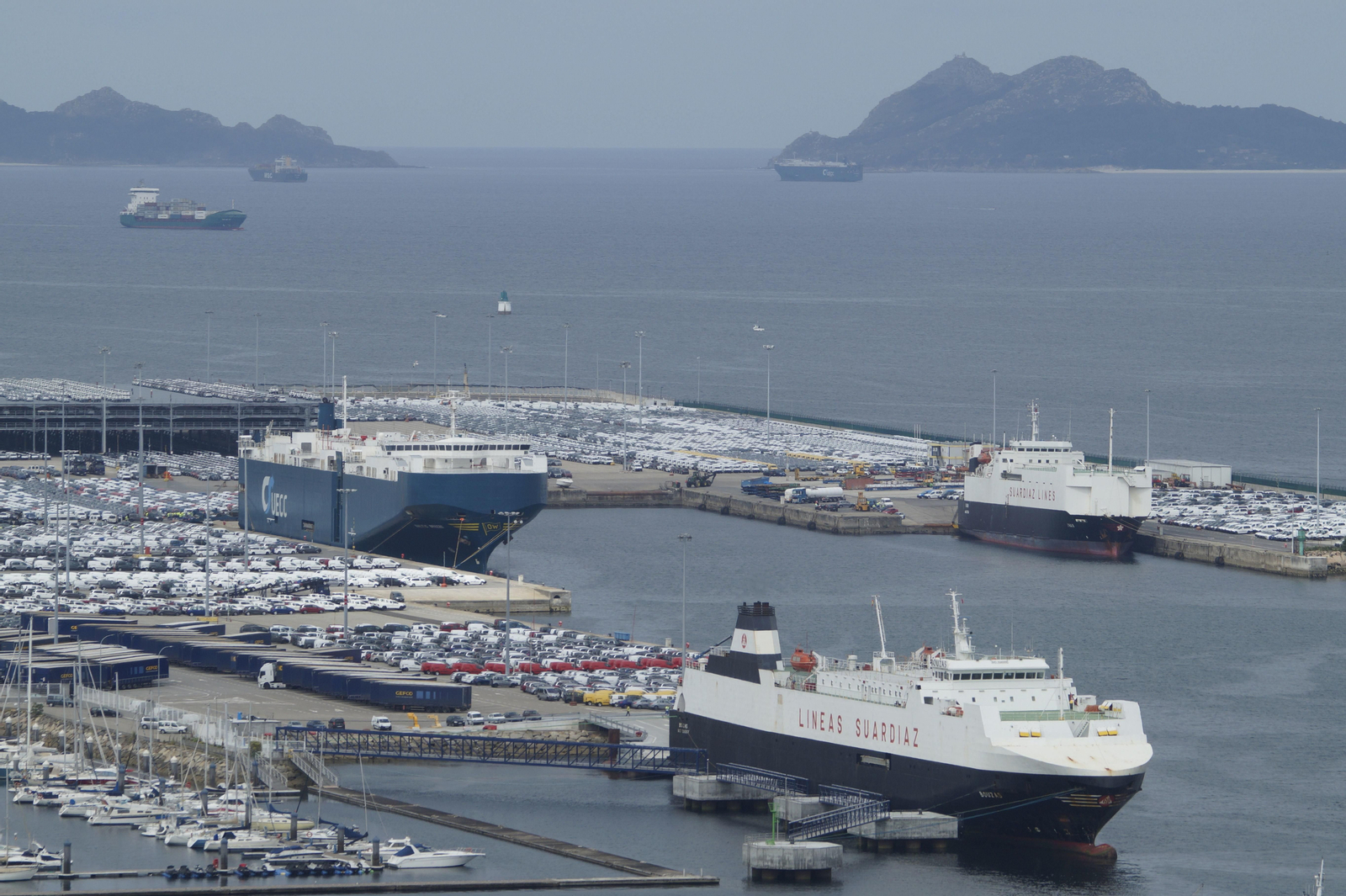 En primerplano, buques cargando vehículos en el muelle de Bouzas y al fondo, portacontenedores esperando para cargar hoy.