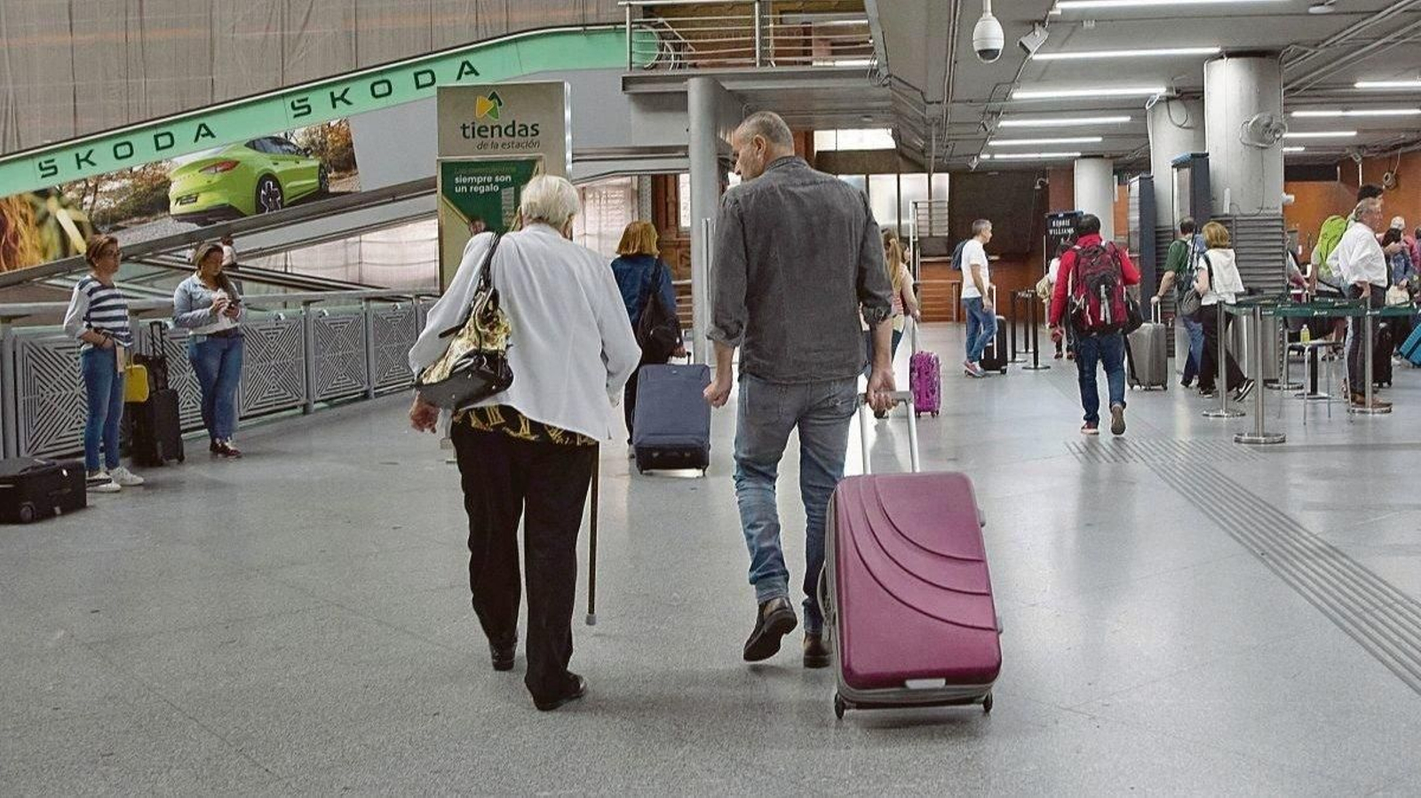 Un hombre acompaña a una mujer mayor antes de subirse a un avión en un aeropuerto.