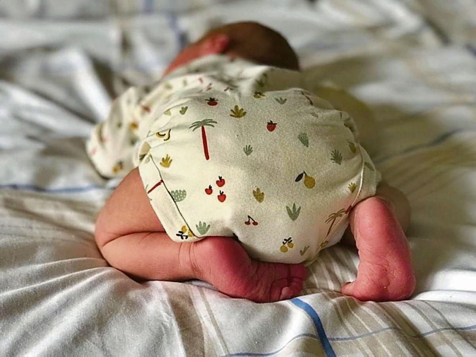 Un bebé recién nacido posado sobre una cama.