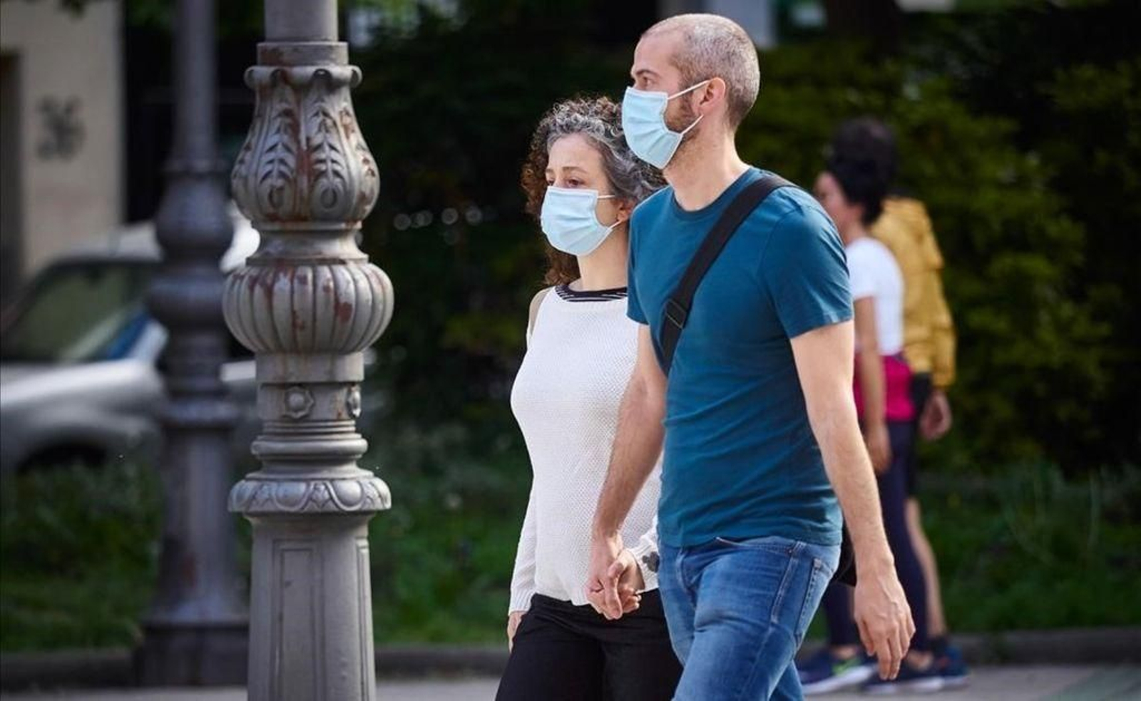 Una pareja, protegida con sus respectivas mascarillas, da un paseo.