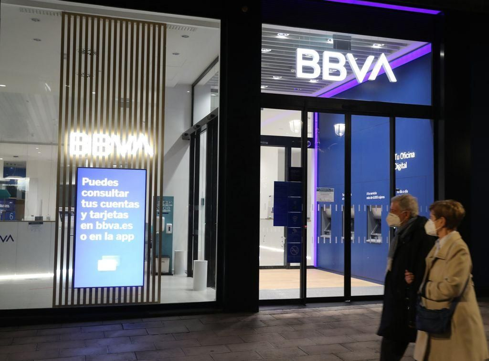 Una pareja pasa ante una oficina del BBVA en Bilbao