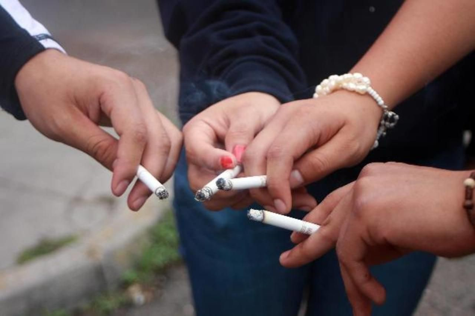 Varios jóvenes fumando a la salida del colegio.