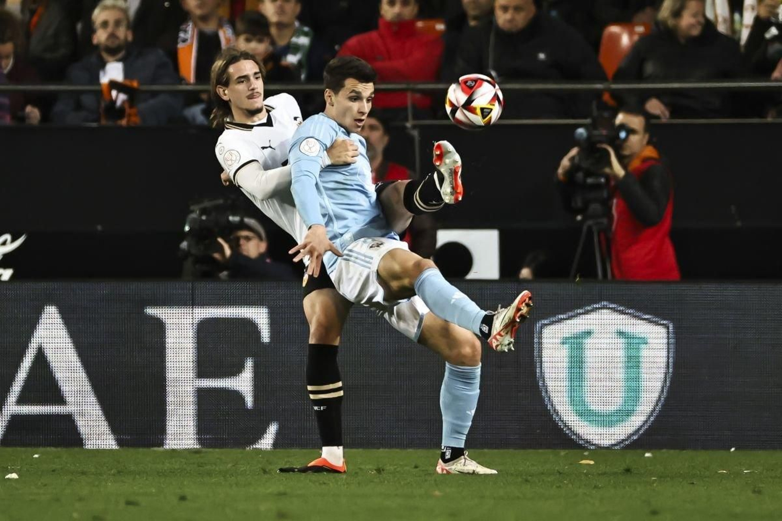 El delantero céltico Anastasios Douvikas trata de controlar el balón de espaldas al joven central valencianista Yarek.