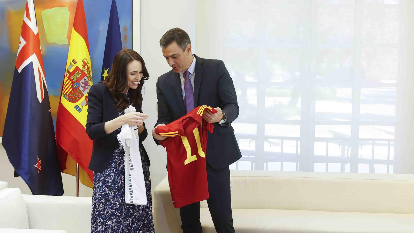El presidente del Gobierno, Pedro Sánchez (d), y la primera ministra de Nueva Zelanda, Jacinda Ardern, se intercambian camisetas de las selecciones de sus respectivos países durante la reunión mantenida en el Palacio de la Moncloa, en el marco de la cumbre de la OTAN que se celebra en Madrid. EFE/Juan Carlos Hidalgo