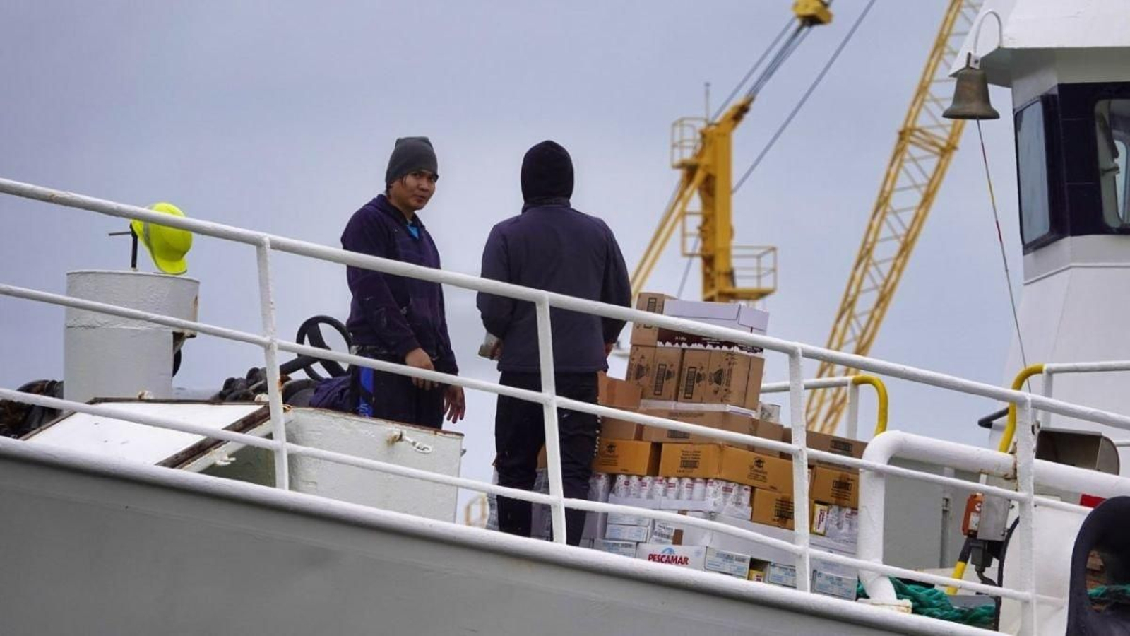 Dos tripulantes sobre la cubierta de un barco pesquero.