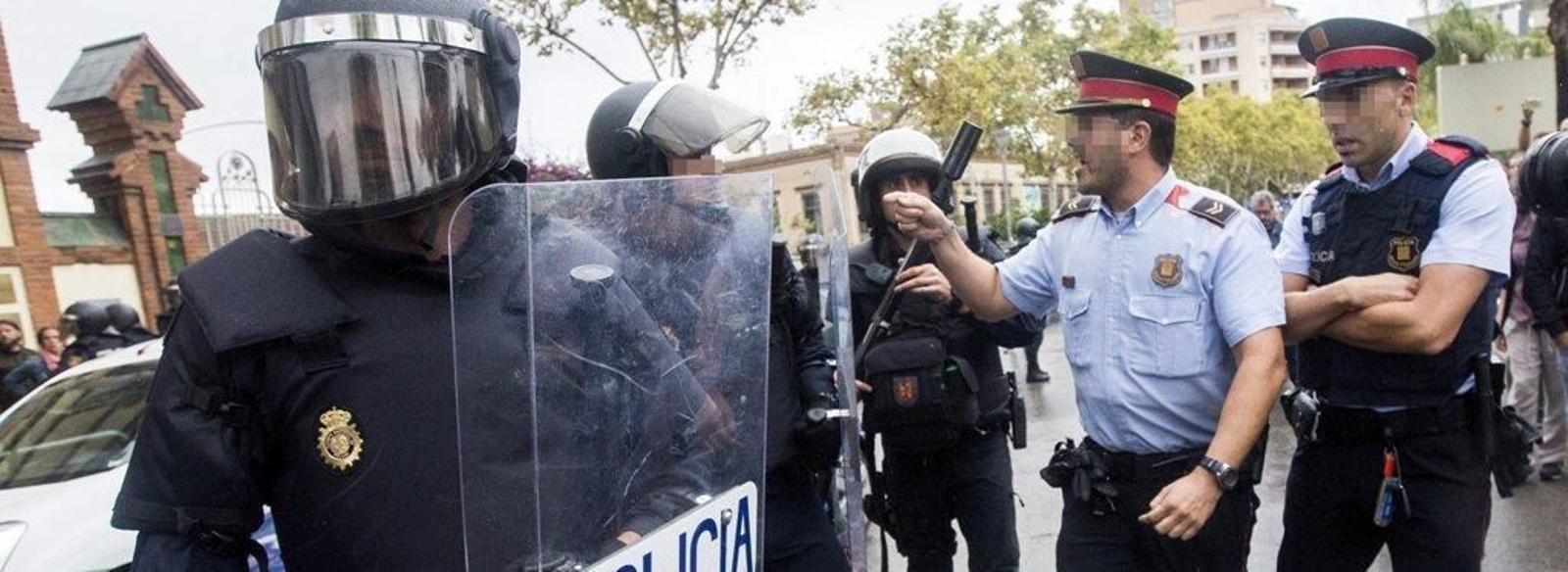 Agentes antidisturbios de la Policía Nacional y de los Mossos d' Esquadra discuten frente al Instituto Can Vilumara de L'Hospitalet de Llobregat.